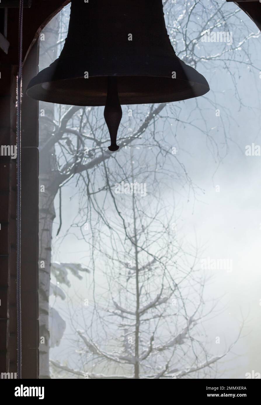 Vista delle montagne innevate, attraverso la campana della chiesa, che si trova nel piccolo villaggio di Kryvorivnya nei Carpazi ucraini. Foto Stock