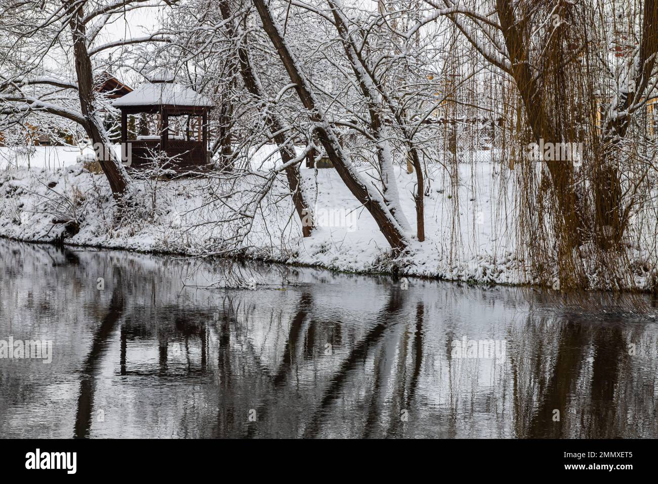 Un piccolo gazebo in legno nelle profondità di una foresta invernale vicino ad un freddo torrente di montagna e persone annegate camminano oltre di essa, risalendo da una valle forestale. Foto Stock Un piccolo gazebo in legno nelle profondità di una foresta invernale vicino ad un freddo torrente di montagna e persone annegate camminano oltre di essa, risalendo da una valle forestale. Foto Stock