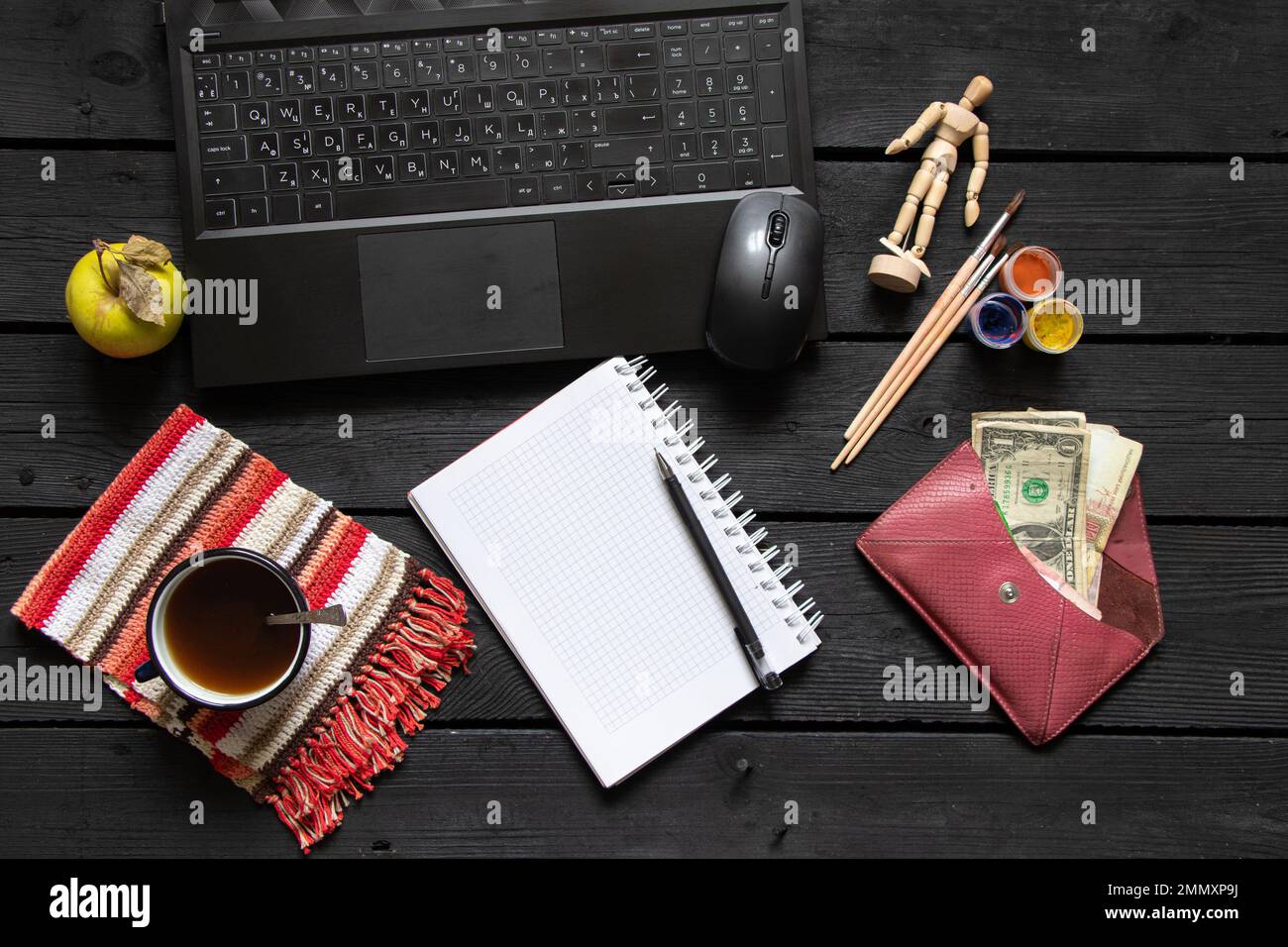 la tazza nera del blocco note del laptop con i soldi del caffè si trovano sul tavolo nero di legno di lavoro, sul laptop sul tavolo di lavoro durante il lavoro, sul processo creativo, sul freelance Foto Stock