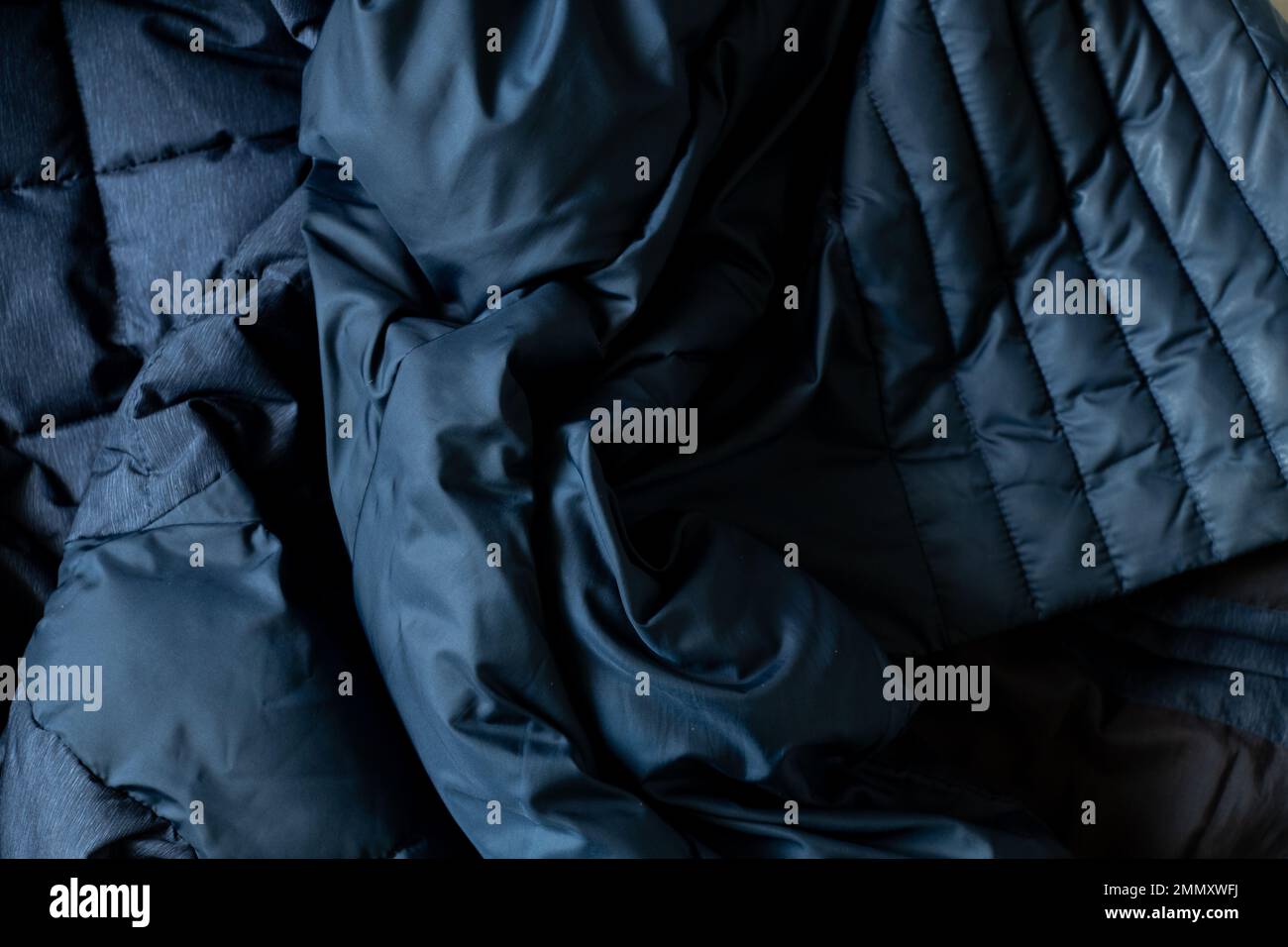 sfondo blu scuro di una giacca invernale soffiata, tessuto rugoso come sfondo Foto Stock