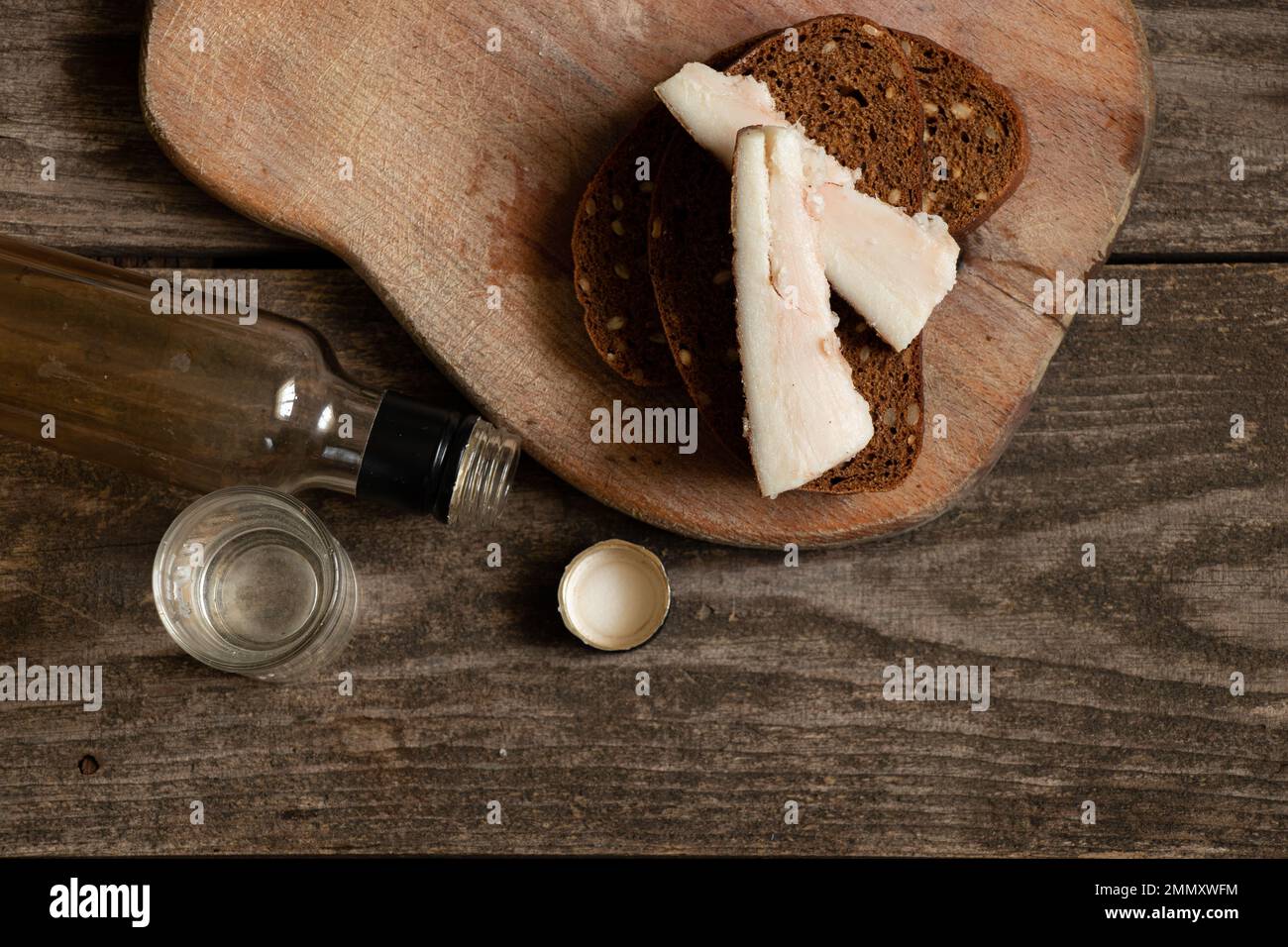 un pezzo di pane con pancetta un bicchiere di vodka sul tavolo, bevande alcoliche e uno spuntino, cattive abitudini, dipendenza da alcol, cibo e bevande Foto Stock