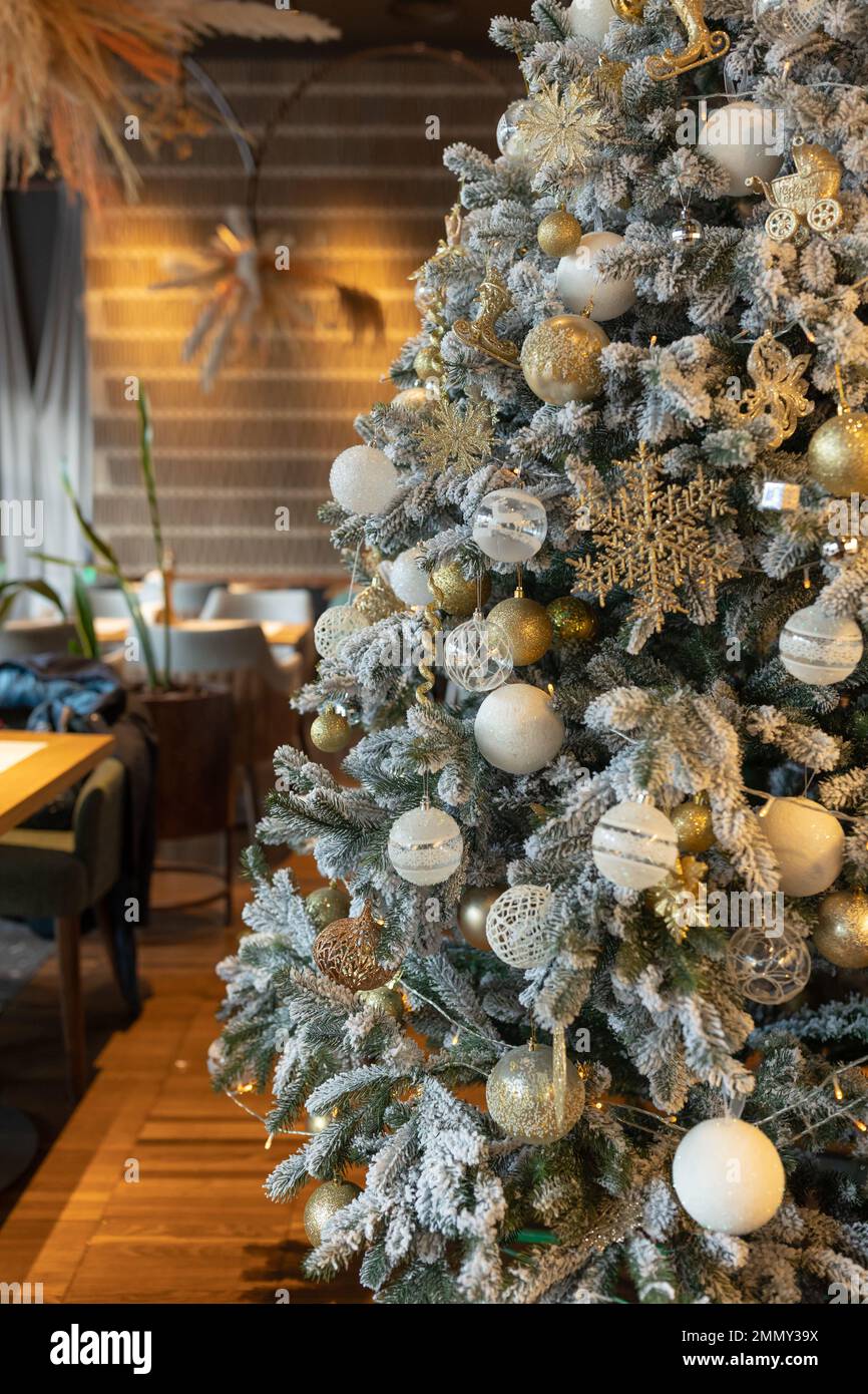 Elegante albero di Natale decorato con palline d'oro e bianche, un orologio  e un mouse si trova accanto al tavolo festivo nel ristorante Foto stock -  Alamy