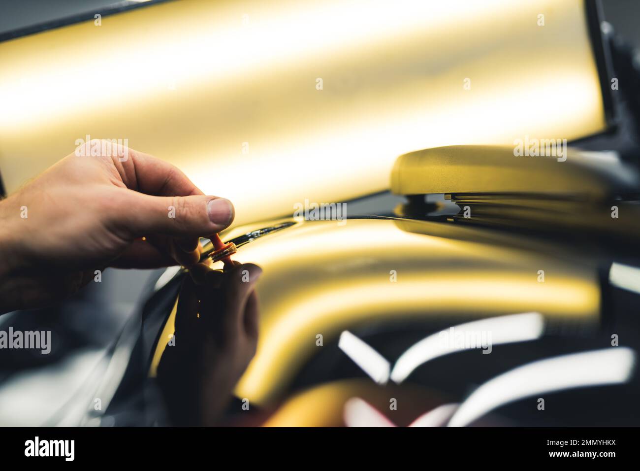 Lampada luminosa utilizzata durante la rimozione di piccole ammaccature su un'auto nera. Primo piano della mano di un meccanico durante il lavoro. Foto di alta qualità Foto Stock