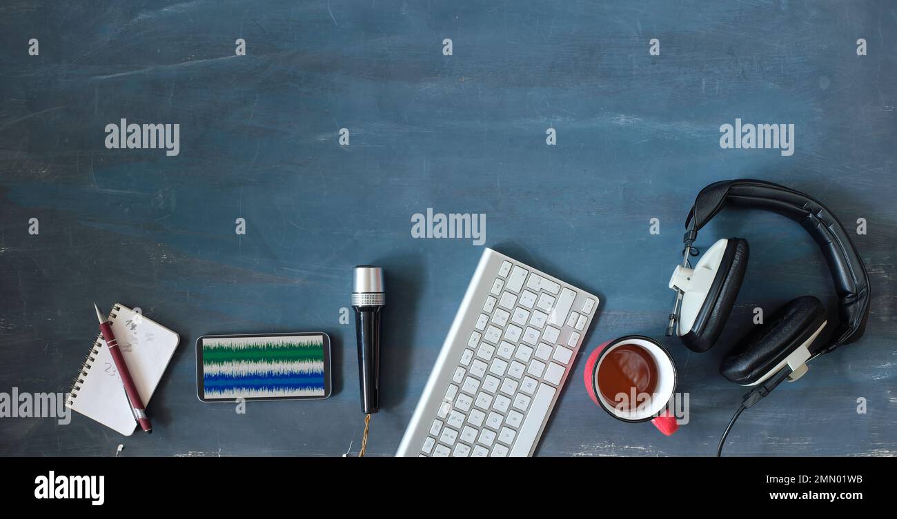 Concetto di musica o podcast con cuffie eleganti, microfono vintage, caffè e tastiera del computer su tavolo blu, vista dall'alto, piatto con spazio copia. Foto Stock