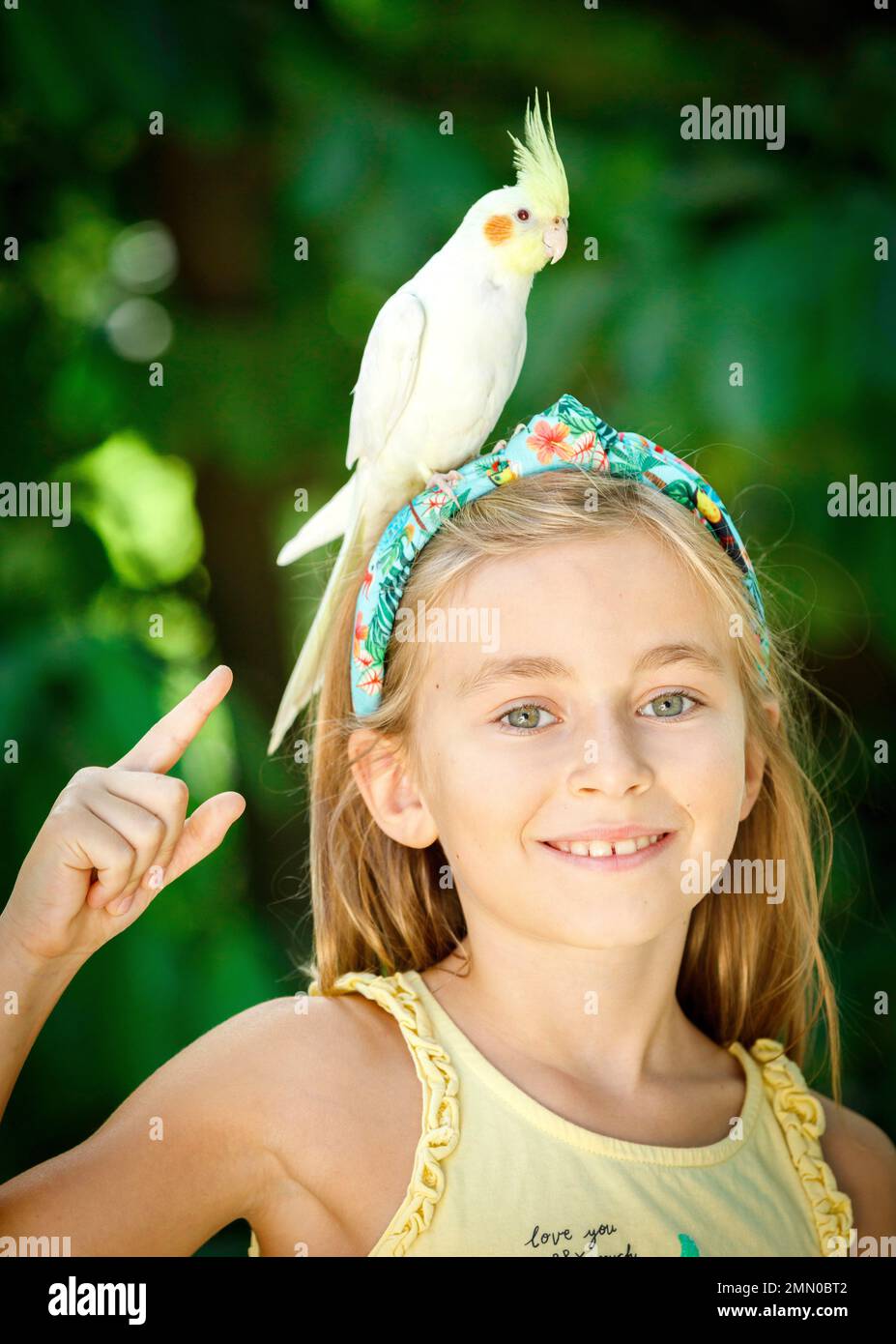 Francia, Haute Garonne, Plaisance du Touch, Zoo Africano, ritratto di una giovane ragazza turista in uno zoo in estate con un uccello sulla sua testa Foto Stock