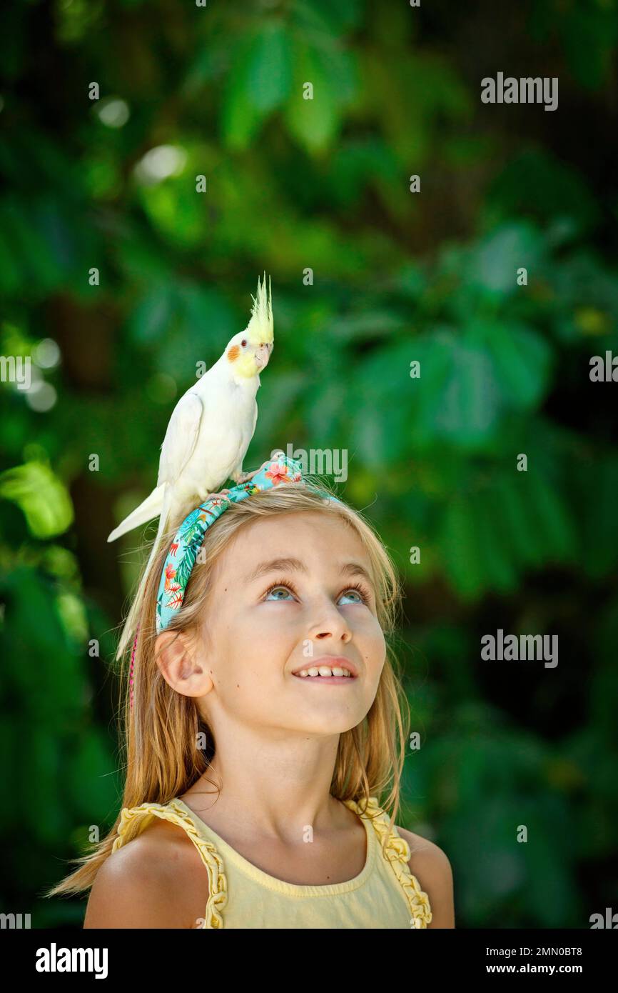 Francia, Haute Garonne, Plaisance du Touch, Zoo Africano, ritratto di una giovane ragazza turista in uno zoo in estate con un uccello sulla sua testa Foto Stock