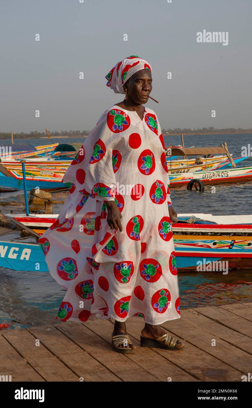 Senegal, il delta di Saloum dichiarato Patrimonio Mondiale dall'UNESCO, donna in boubou colorato nel mezzo delle canoe sul pontile del molo Ndangane Foto Stock