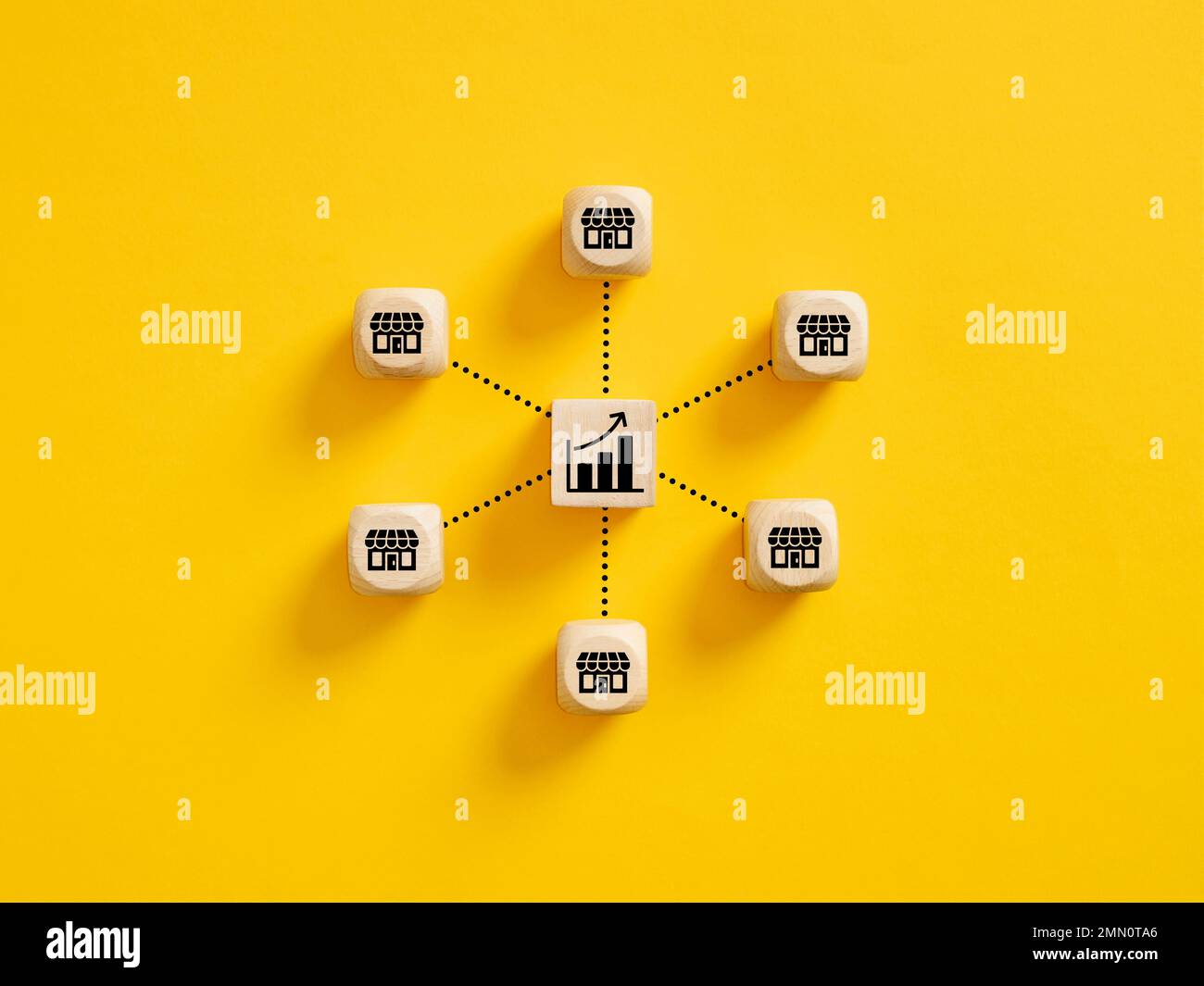 Crescita delle vendite aziendali. Espansione dei negozi in franchising e aumento del concetto di redditività. Cubi di legno con simboli grafici ascendenti e negozio collegati con spirito Foto Stock