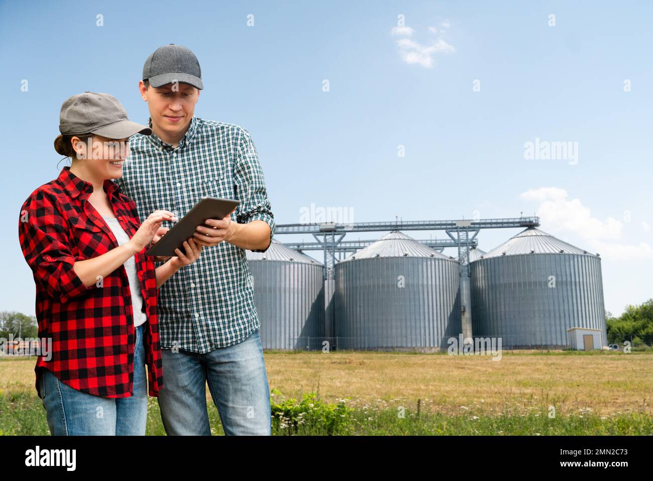 Agricoltori con tablet digitale di fronte al silo agricolo Foto Stock
