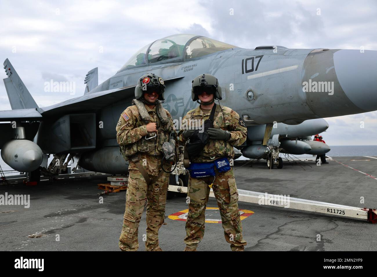 Soldiers from B Company, 3-2 General Support Aviation Battalion, 2nd Combat Aviation Brigade posa di fronte a un US Navy F/A-18 Hornet. Soldiers from B Company, 3-2 General Support Aviation Battalion, 2nd Combat Aviation Brigade condusse atterraggi con elicotteri CH-47F Chinook sull'unico portaerei della Marina statunitense, USS Ronald Reagan (CVN 76), nelle acque ad est della penisola coreana il 26 settembre 2022. Le qualifiche di atterraggio sul ponte sono condotte per certificare i membri dell'equipaggio e i piloti che atterrano su una nave. Questa formazione è stata condotta in parte con il Marit Foto Stock