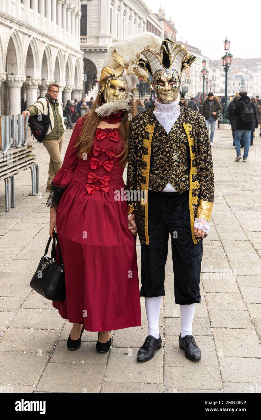 Giovane coppia in costume medievale di carnevale, cappelli con piume e  maschere in Piazza San Marco a Venezia Foto stock - Alamy