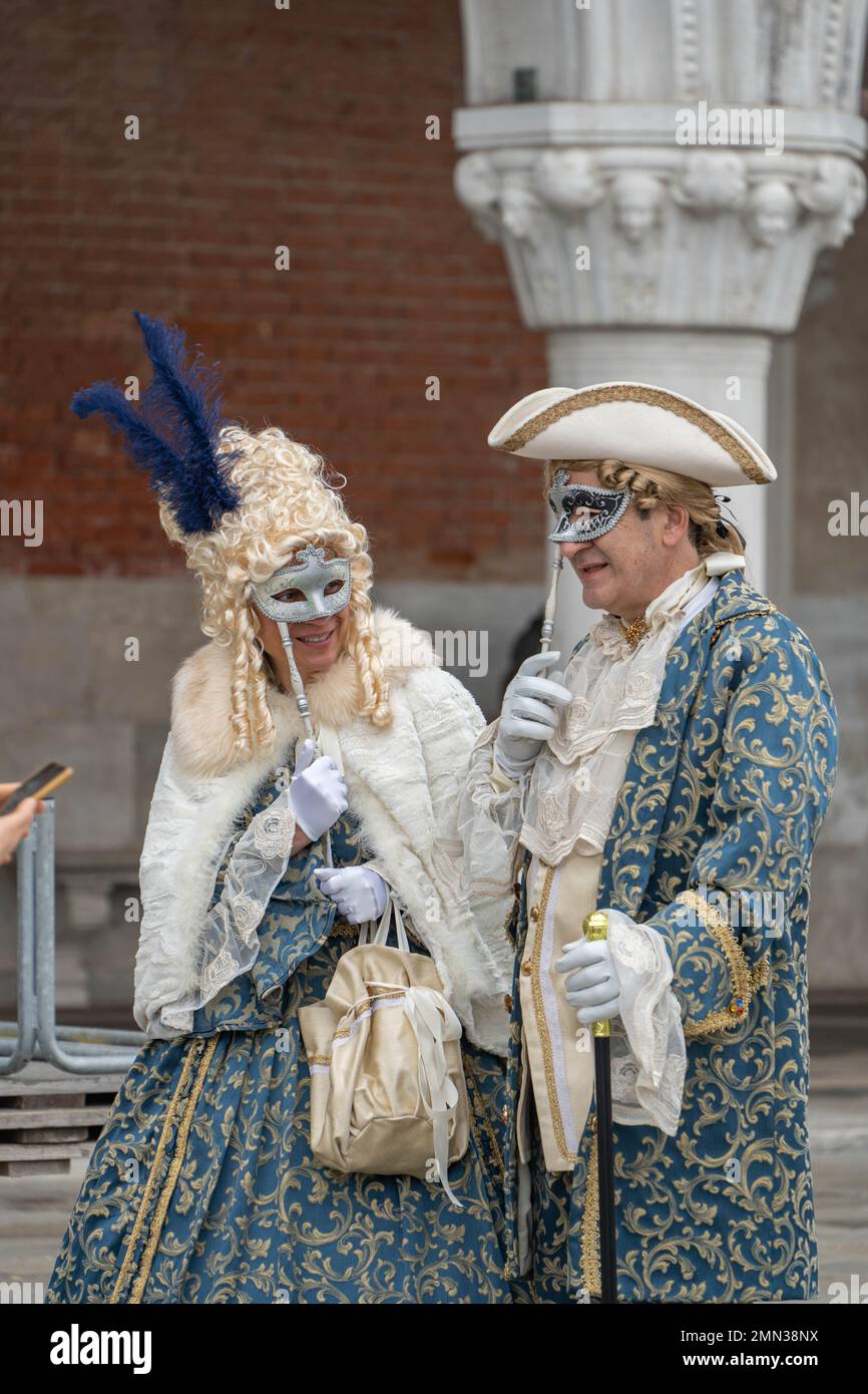 Uomo e donna in costume di carnevale medievale azzurro chiaro, parrucche,  cappelli e maschere in Piazza San Marco a Venezia Foto stock - Alamy