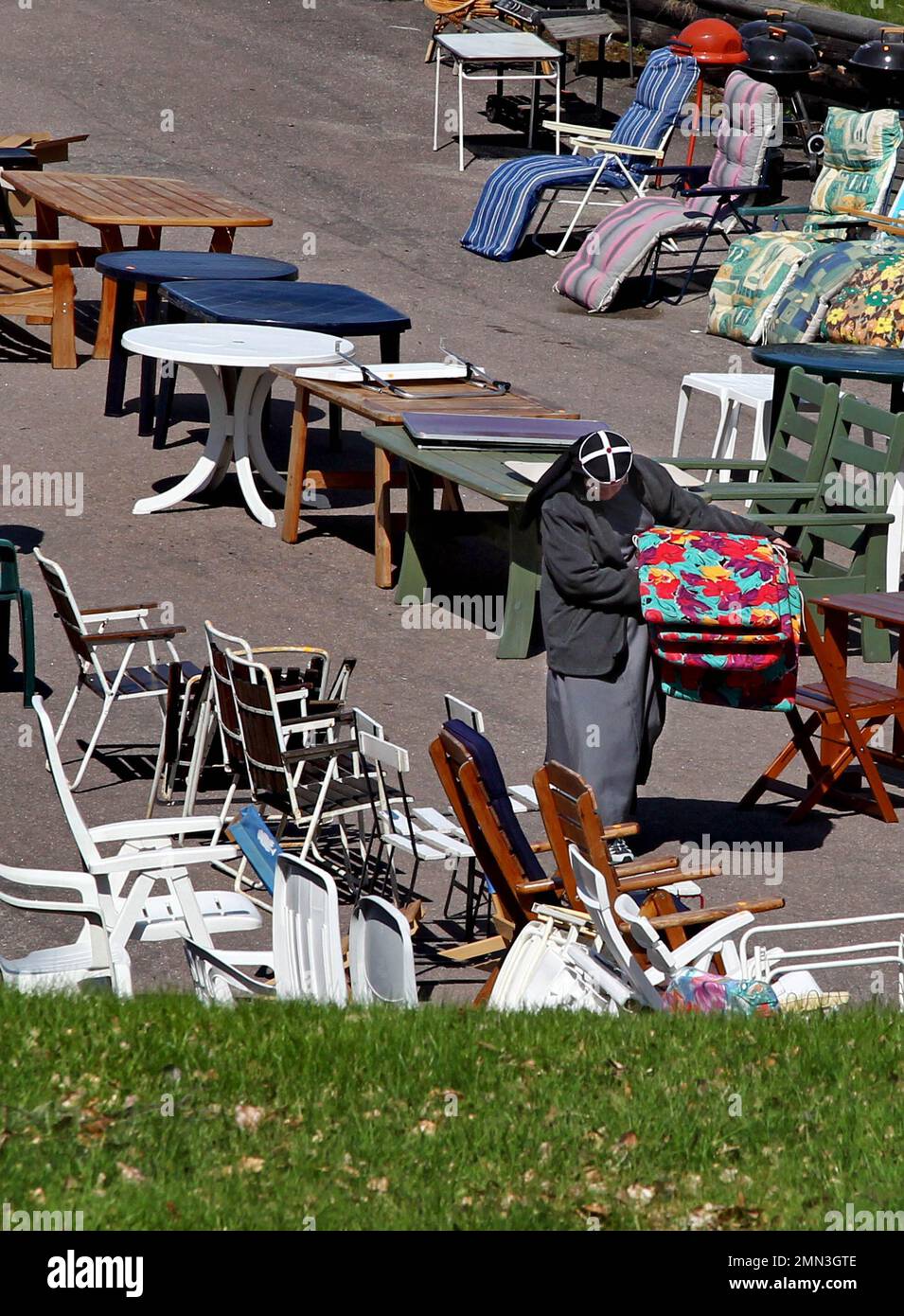 Una suora trasporta i cuscini del divano e guarda i mobili esterni ad un mercato delle pulci questo sabato soleggiato. Ora il caldo estivo è finalmente in arrivo. Questo fine settimana e bene nella prossima settimana, sarà soleggiato e caldo in quasi tutto il paese. Foto Stock