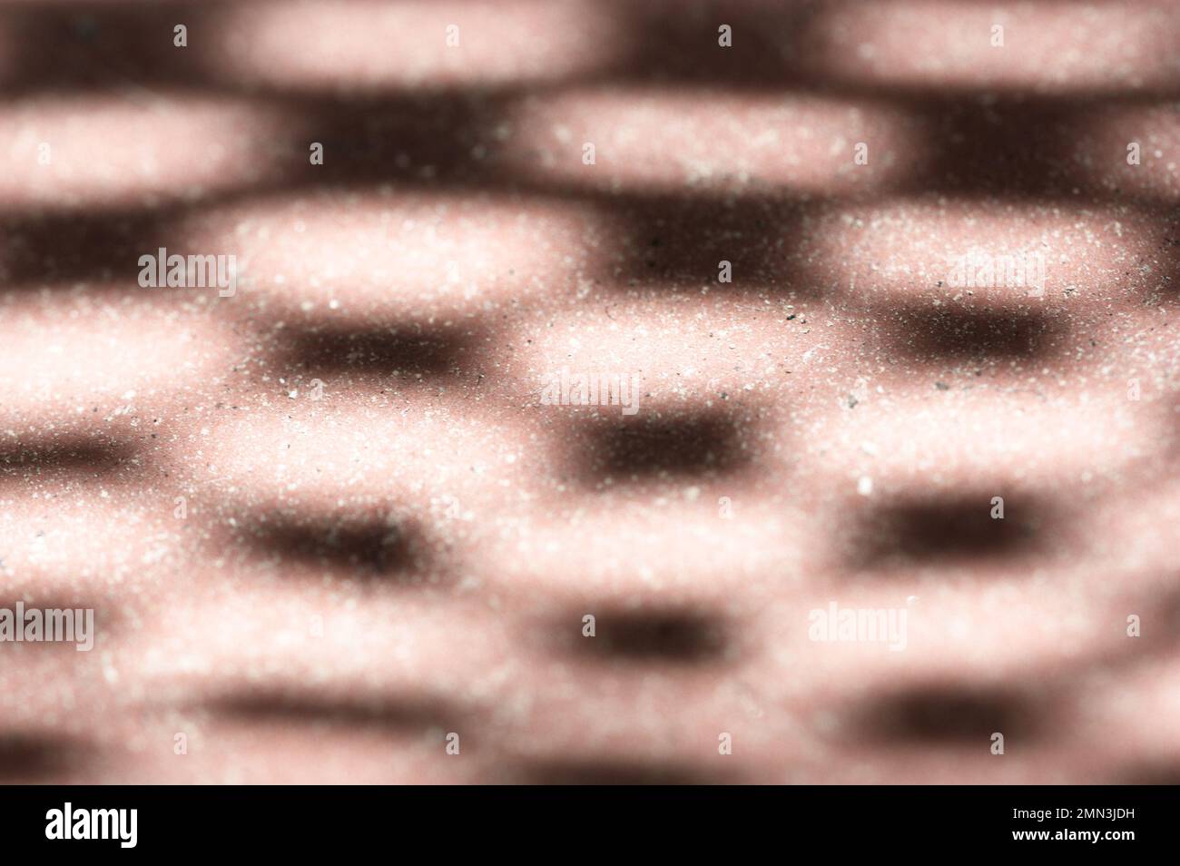 Modello generato dalla luce solare che passa attraverso una superficie di apertura che proietta un'ombra su una superficie marrone Foto Stock
