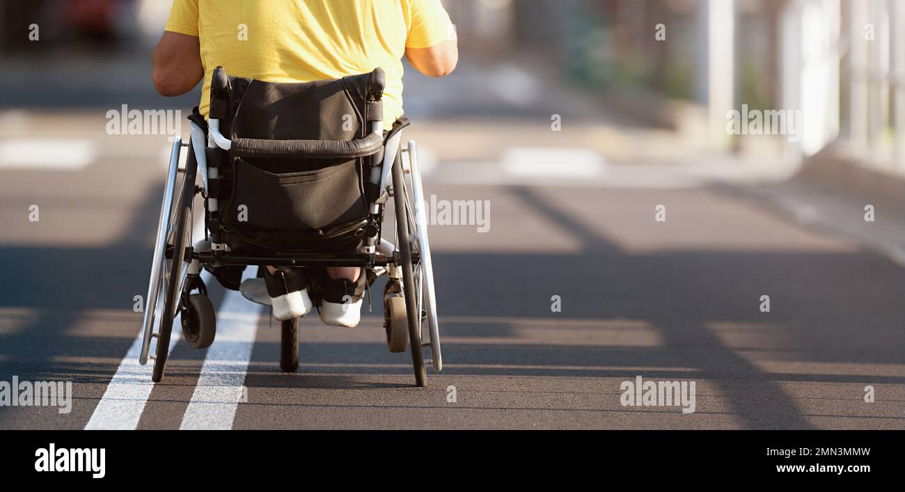 Uomo disabile in carrozzina su strada Foto Stock