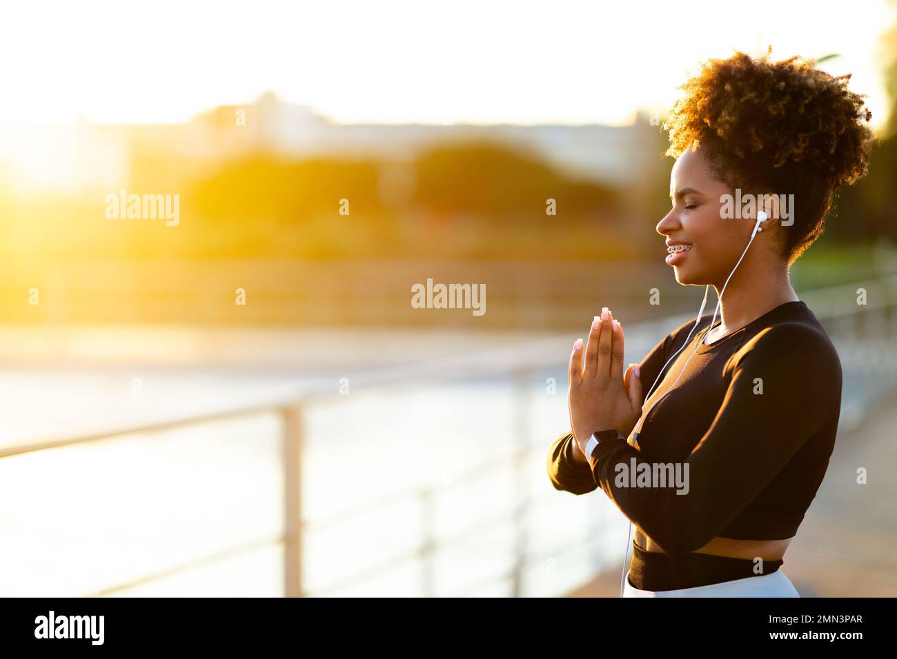 Yoga all'aperto. Ritratto di giovane donna nera sorridente meditando fuori Foto Stock