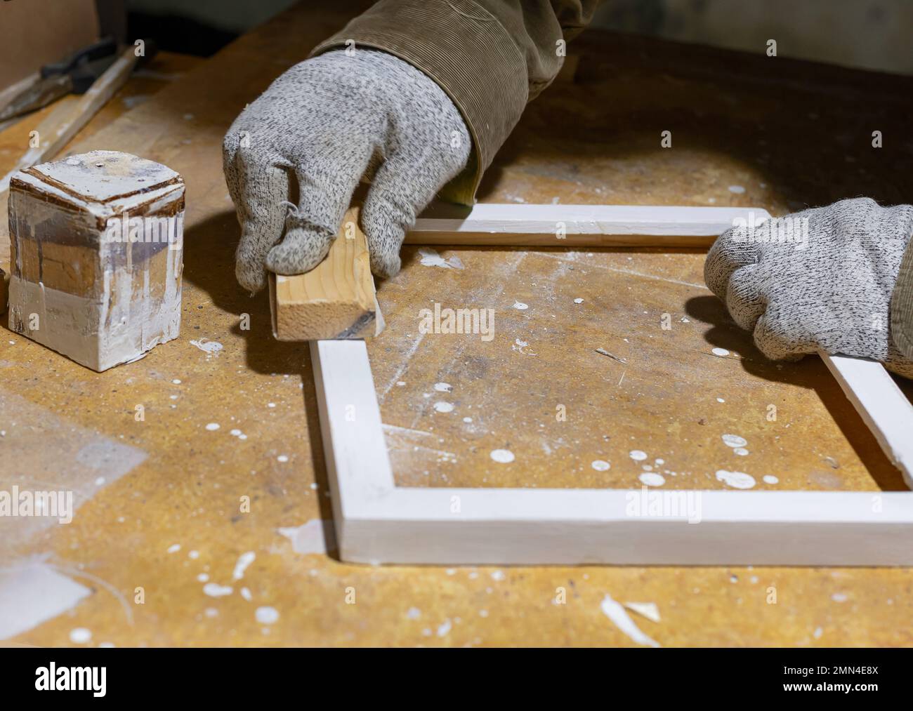 Primo piano di una cornice di legno che un hobbista leviga con carta vetrata Foto Stock