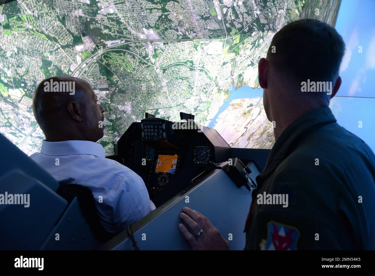 Harry Cooke, Dipartimento del lavoro del New Jersey, gestisce un simulatore di volo F-16 Fighting Falcon come U.S. Air Force Lt. Col. Gregory P. Poston, II, 177th Operations Group Commander, osserva la 177th Fighter Wing della New Jersey Air National Guard a Egg Harbor Township, New Jersey, 28 settembre 2022. I membri del gabinetto del governatore del New Jersey, la New Jersey Economic Development Authority, e i leader del New Jersey Department of Military and Veterans Affairs hanno ricevuto un briefing missionario dal comandante dell’Ala e hanno poi girato il 177th° FW, osservando diversi dimostranti operativi Foto Stock