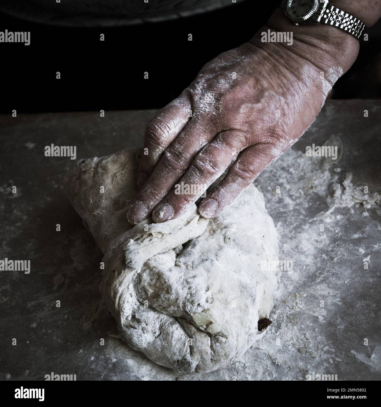 Le mani della nonna della donna impastano la pasta del pane su una superficie infarinata Foto Stock