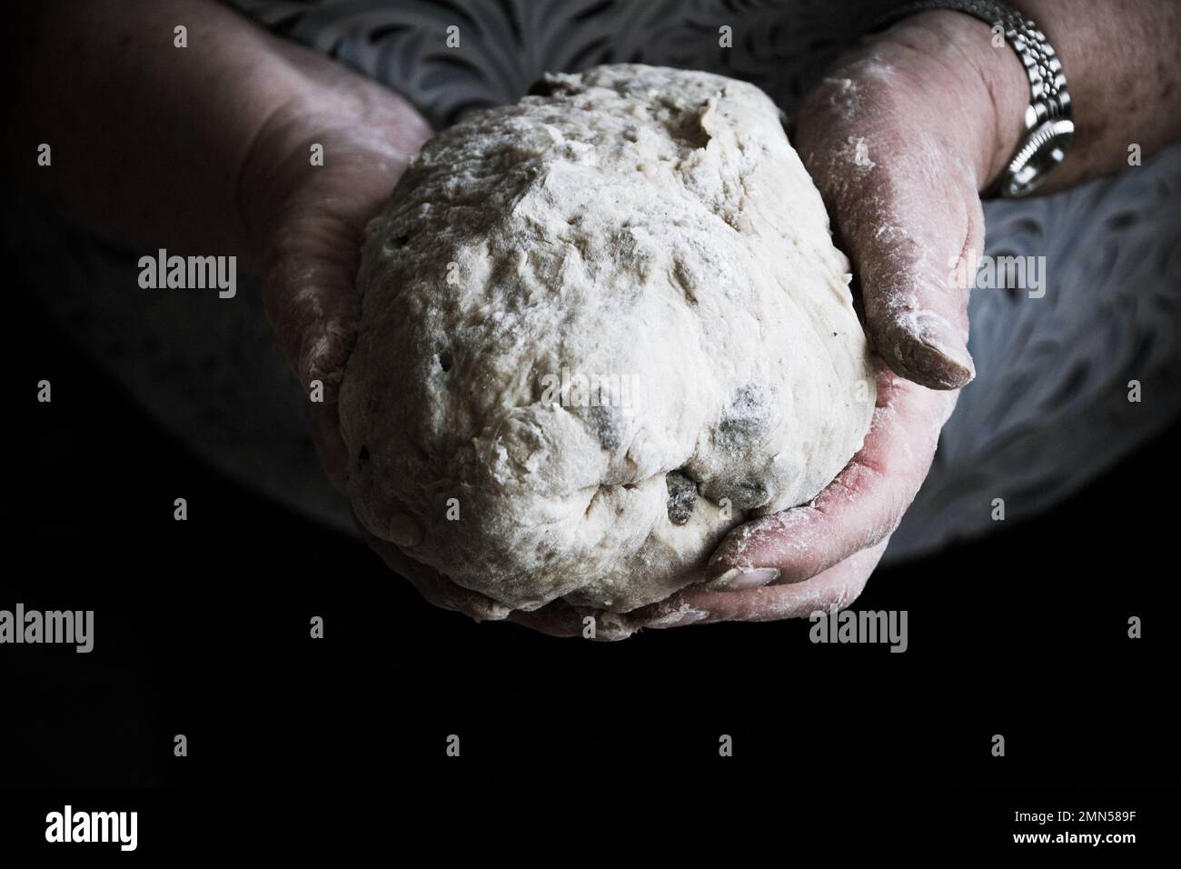 Mani della nonna della donna che tiene una sfera della pasta del pane Foto Stock