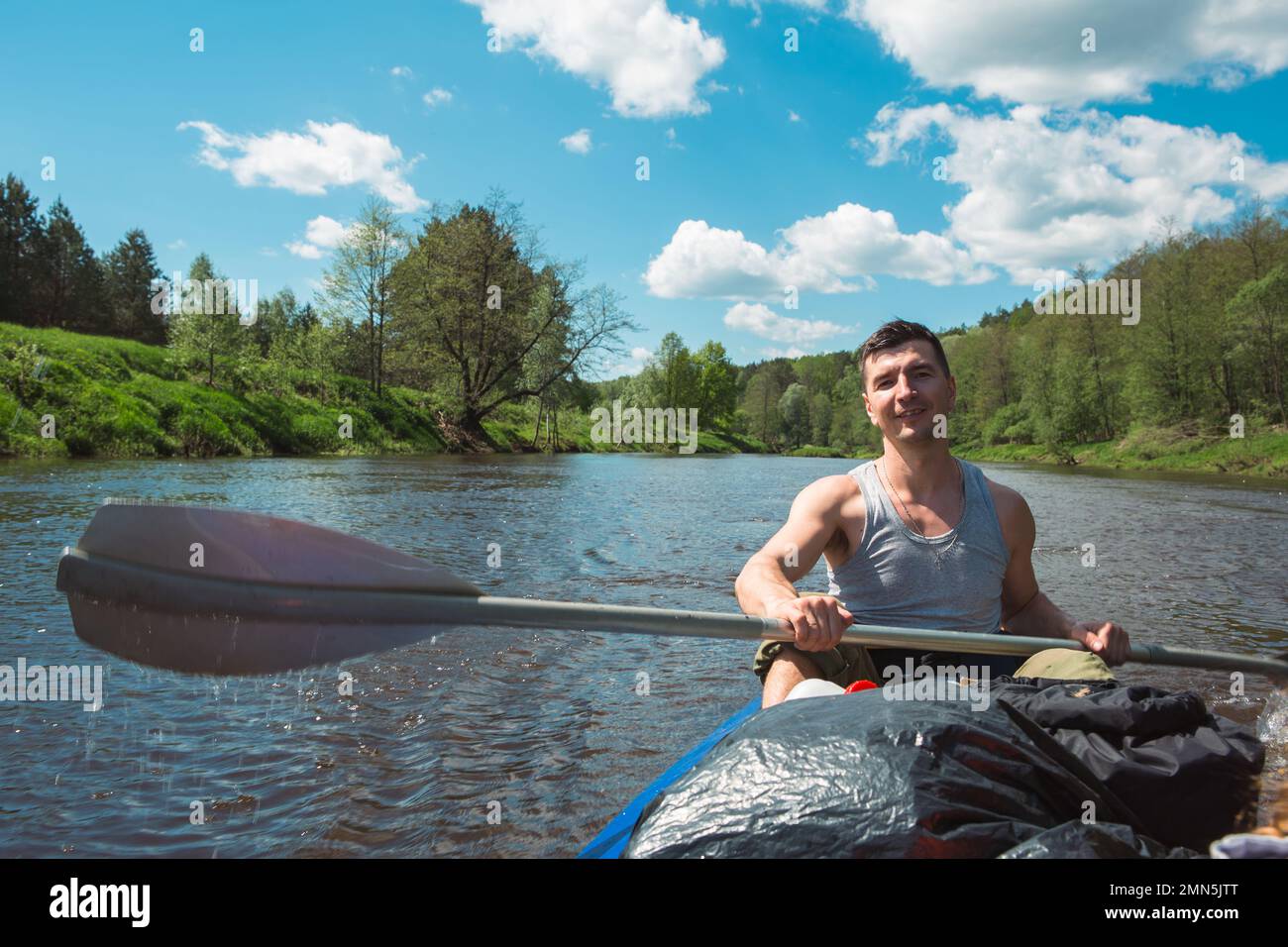 Uomo in kayak gita in barca a remi sul fiume, un'escursione in acqua, un'avventura estiva. Eco-friendly e turismo estremo, uno stile di vita attivo e sano Foto Stock