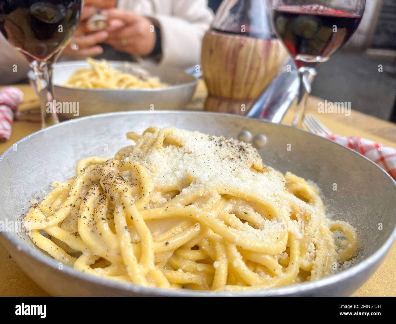 cucina italiana, primo piano deliziosa pasta fatta a mano con formaggio sul tavolo. Spaghetti tipici e tradizionali italiani e vino rosso locale a tavola a Roma, IT Foto Stock
