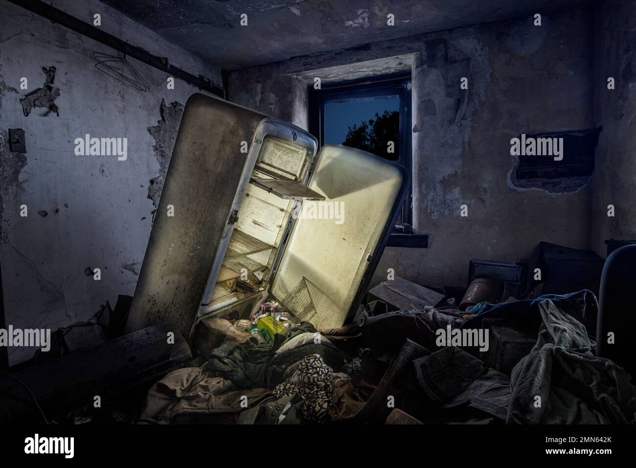 Frigorifero abbandonato con luce luminosa in camera piena di rifiuti, Pennsylvania, Stati Uniti Foto Stock