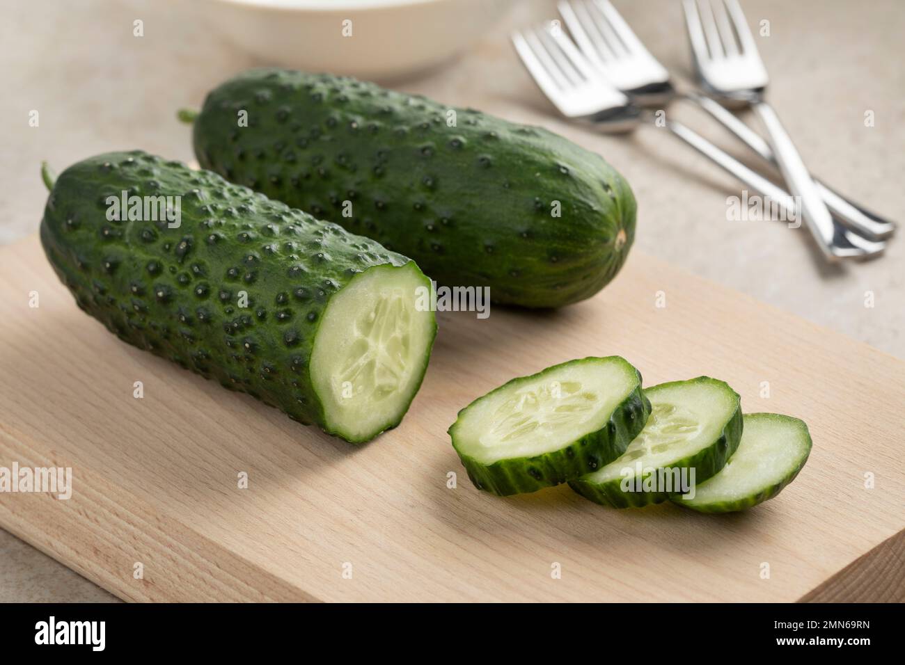 Cetriolo di snack sano fresco intero e affettato, Marketmore, primo piano su un tagliere Foto Stock