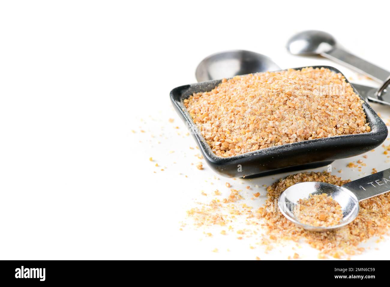 Farina integrale in ciotola nera e misurino isolato su fondo bianco, preparazione di panetteria e pane concetto Foto Stock