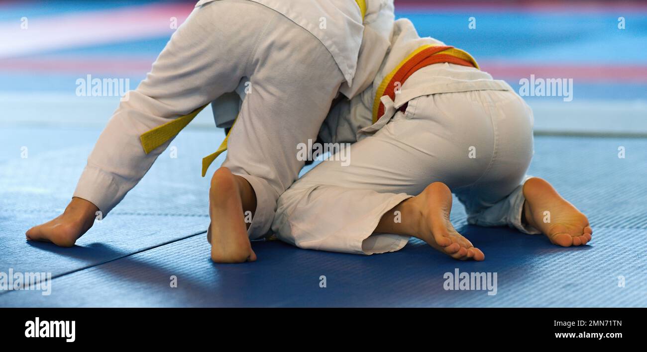 Kid judo, l'arte marziale dei bambini nella competizione della sala alla scuola di judo, due piccoli ragazzi in lotta, sforzo e raggiungimento Foto Stock