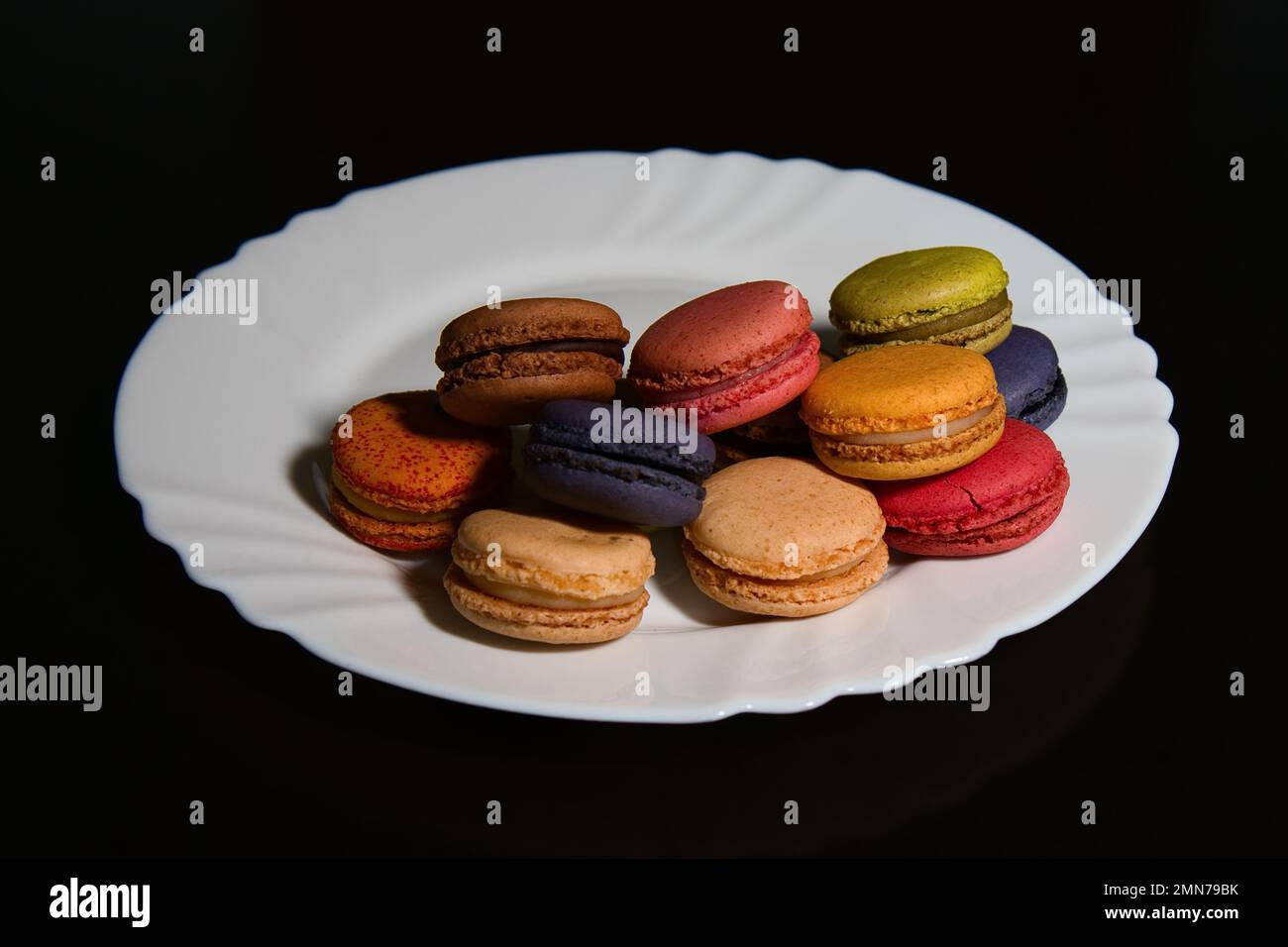 Macaron su un piatto su sfondo nero Foto Stock