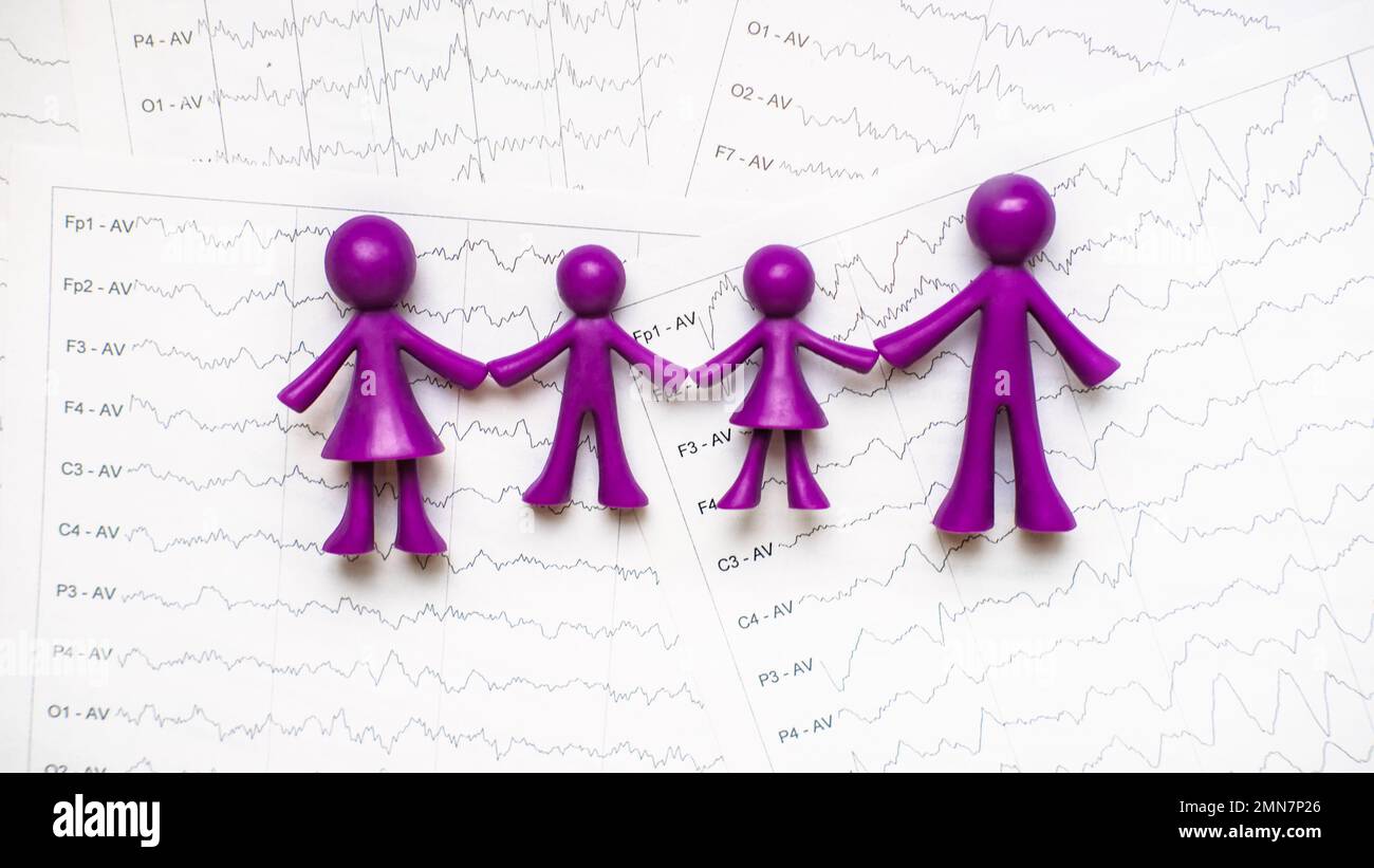 Giornata internazionale dell'epilessia, consapevolezza dell'epilessia. Giocattolo viola per adulti e bambini, famiglia su onda cerebrale su elettroencefalogramma EEG per l'epilessia Foto Stock