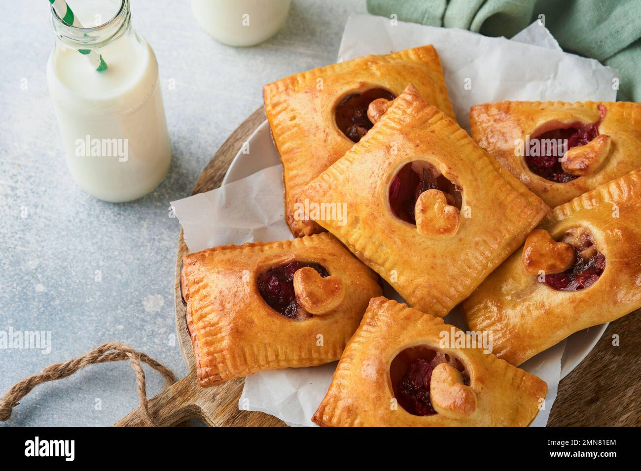 Torte a forma di cuore di San Valentino. Mini pasta sfoglia o torte farcite a mano con mela e cospargere lo zucchero in polvere nel piatto. Idea per romantico fatto in casa Foto Stock