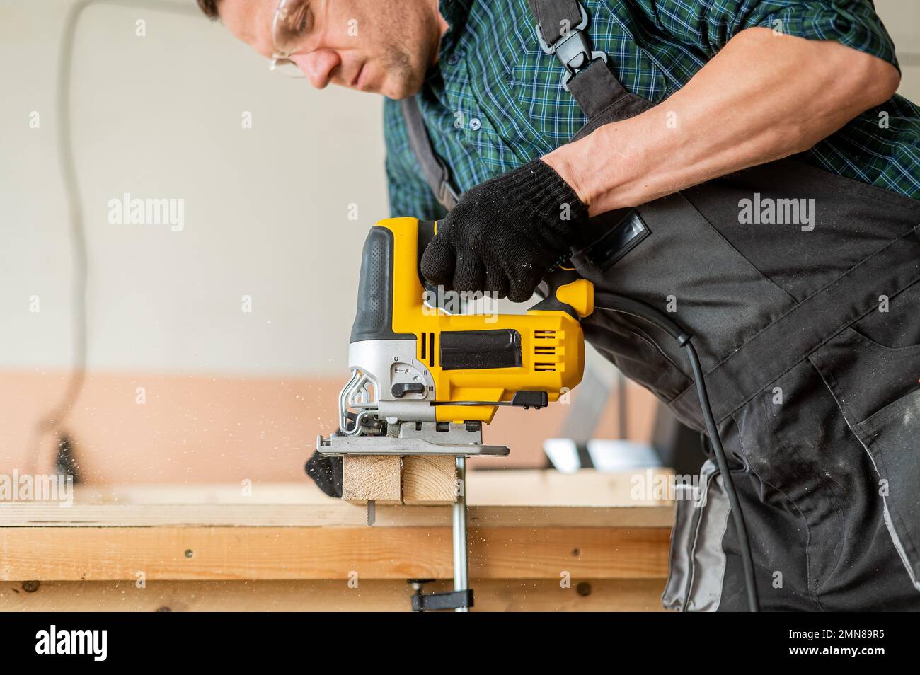 Un uomo taglia una tavola di legno con un seghetto elettrico in un'officina  Foto stock - Alamy