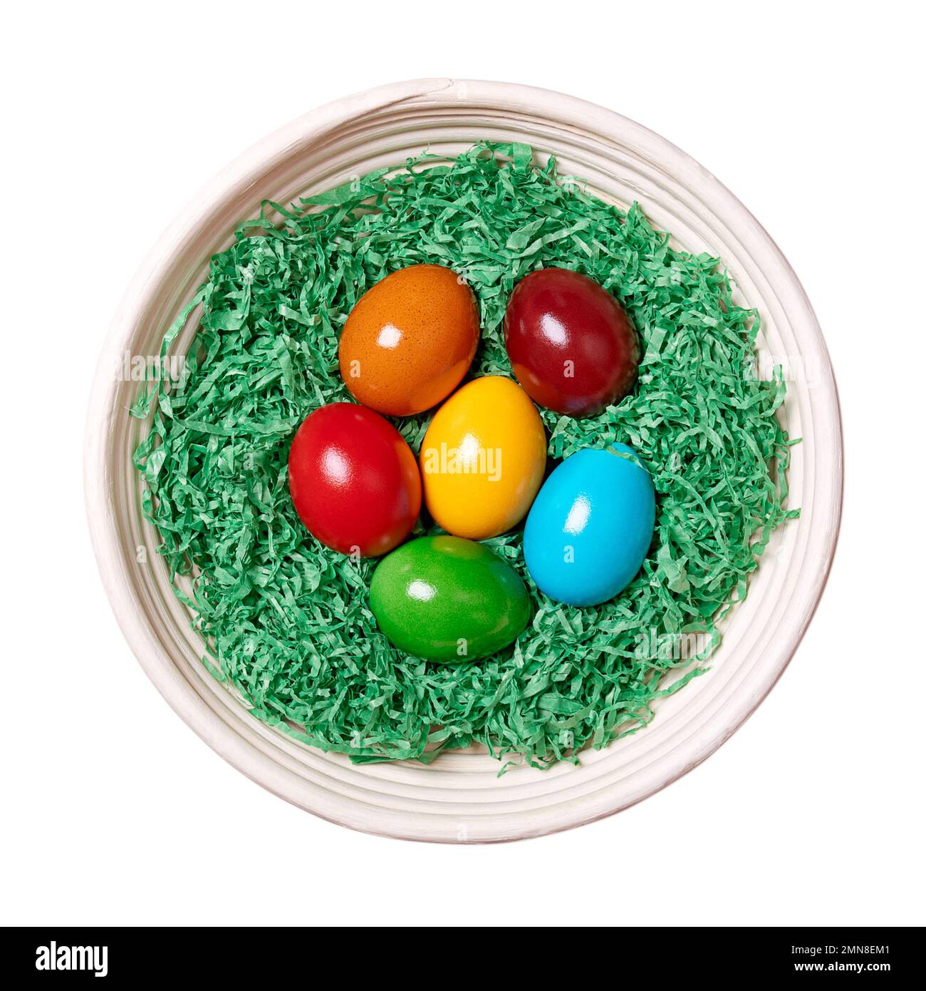 Nido di lana di legno con uova di Pasqua in un cesto di rattan. Uova paschal colorate, disposte in un nido di carta verde grattugiata. Foto Stock