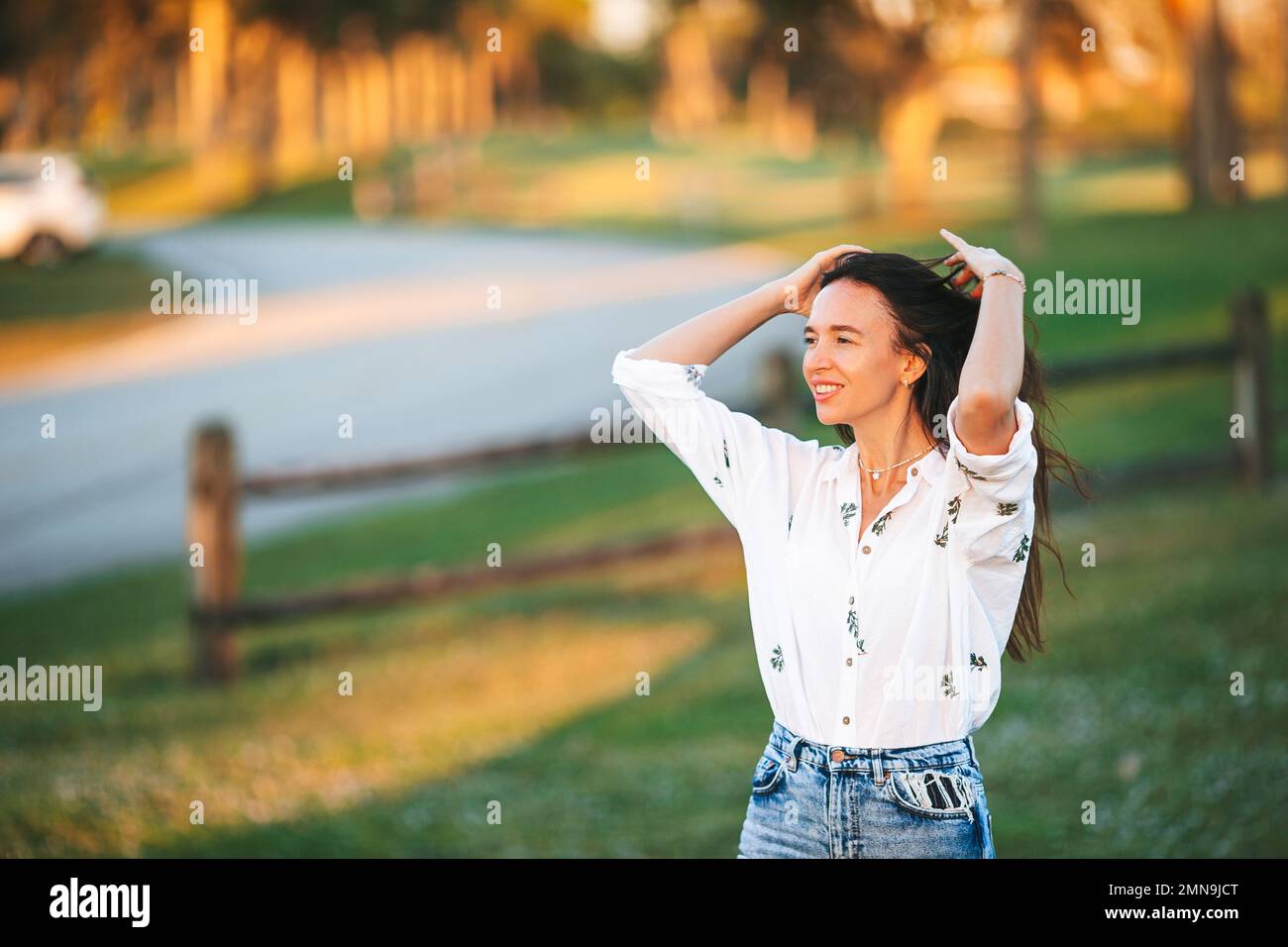 Ritratto di felice giovane donna all'aperto nel parco al tramonto Foto Stock