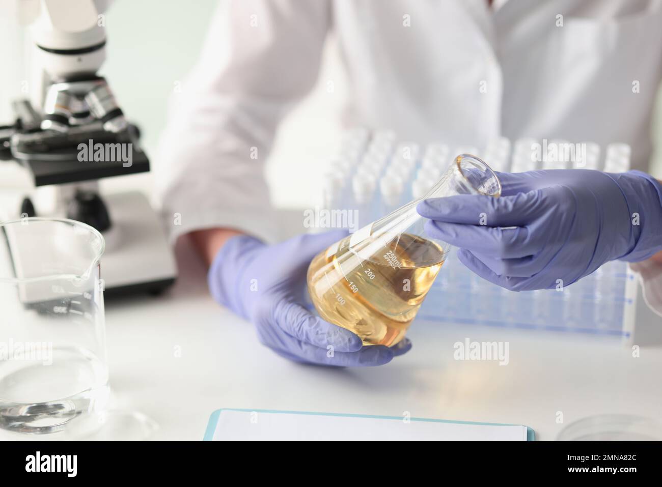 Scienziato che misura il liquido giallo in una beuta presso un laboratorio chimico. Foto Stock