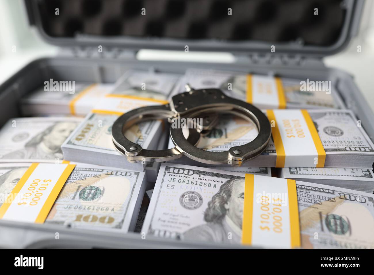 Primo piano di manette su pile di banconote in dollari. Foto Stock