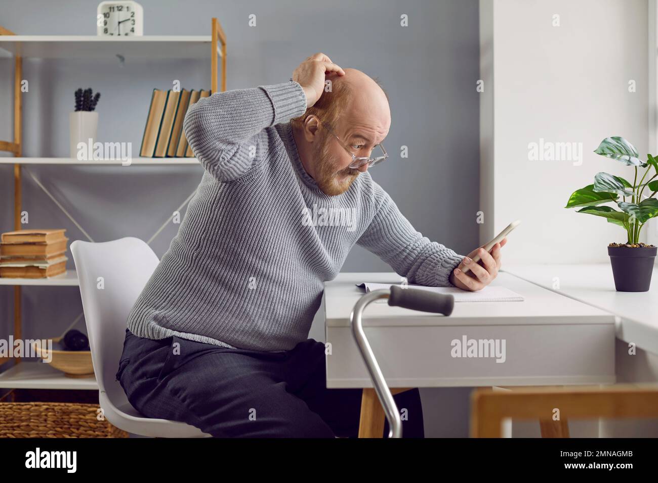 Uomo anziano che si confonde mentre usa un'applicazione sul suo moderno telefono cellulare Foto Stock