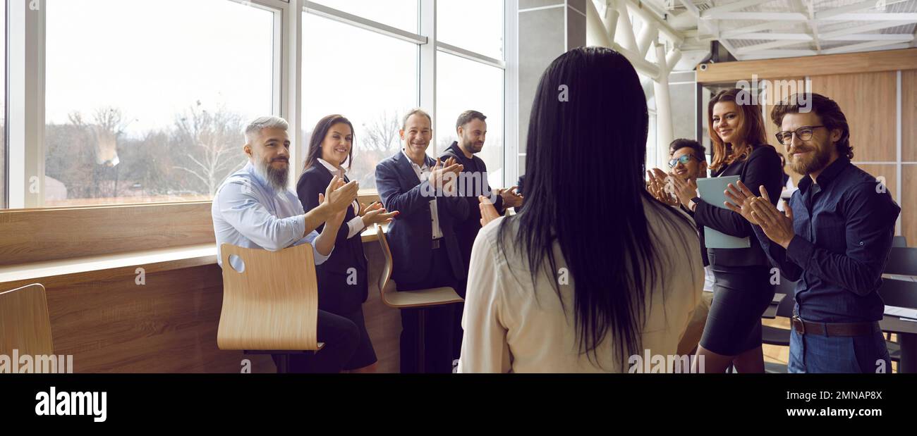 Persone di successo impiegati applaudire dipendente femminile di stand aziendali con il ritorno alla fotocamera Foto Stock