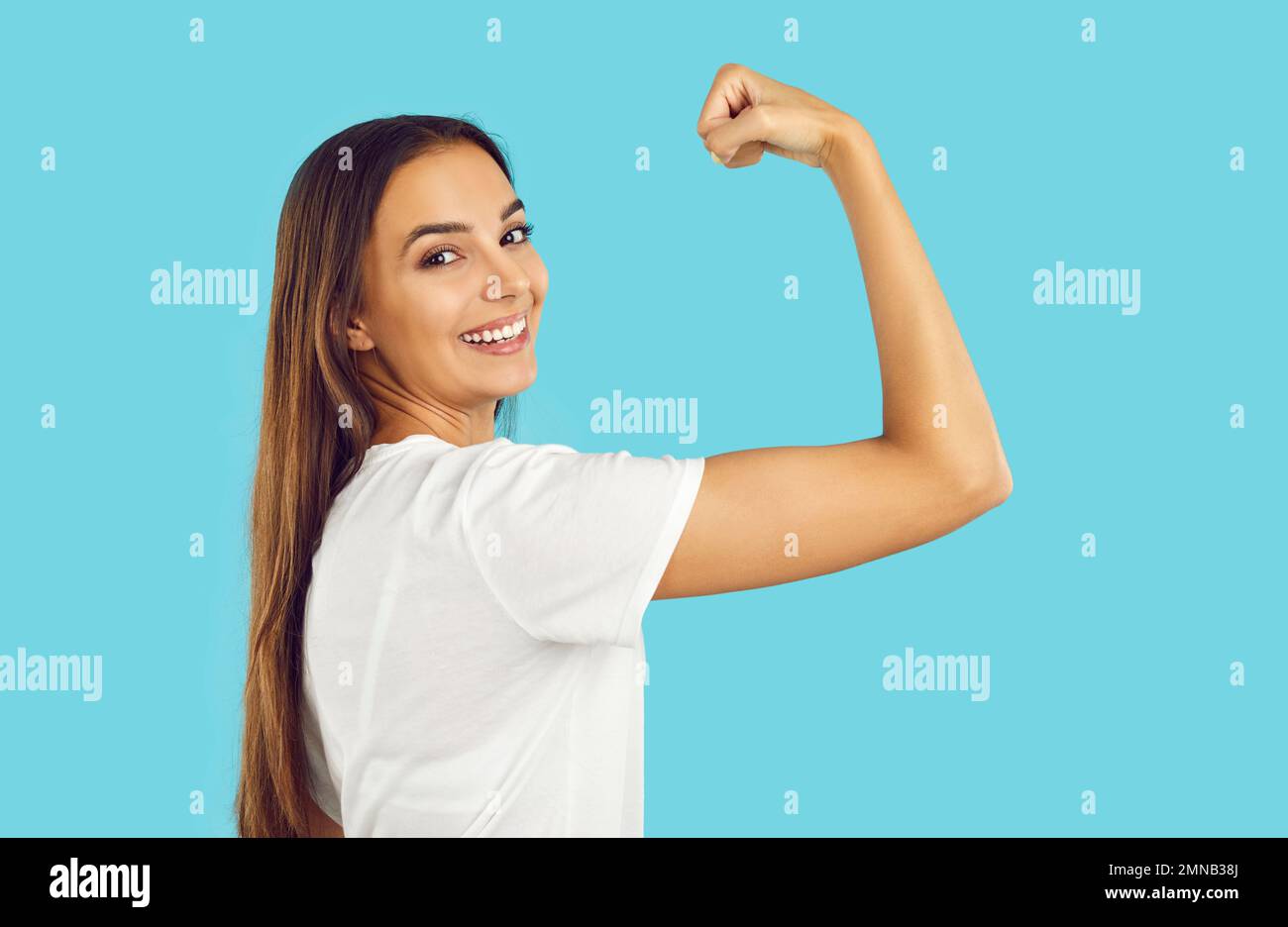 Donna felice sicura sorridente forte e mostrando il suo braccio flessibile di potenza su sfondo blu. Foto Stock