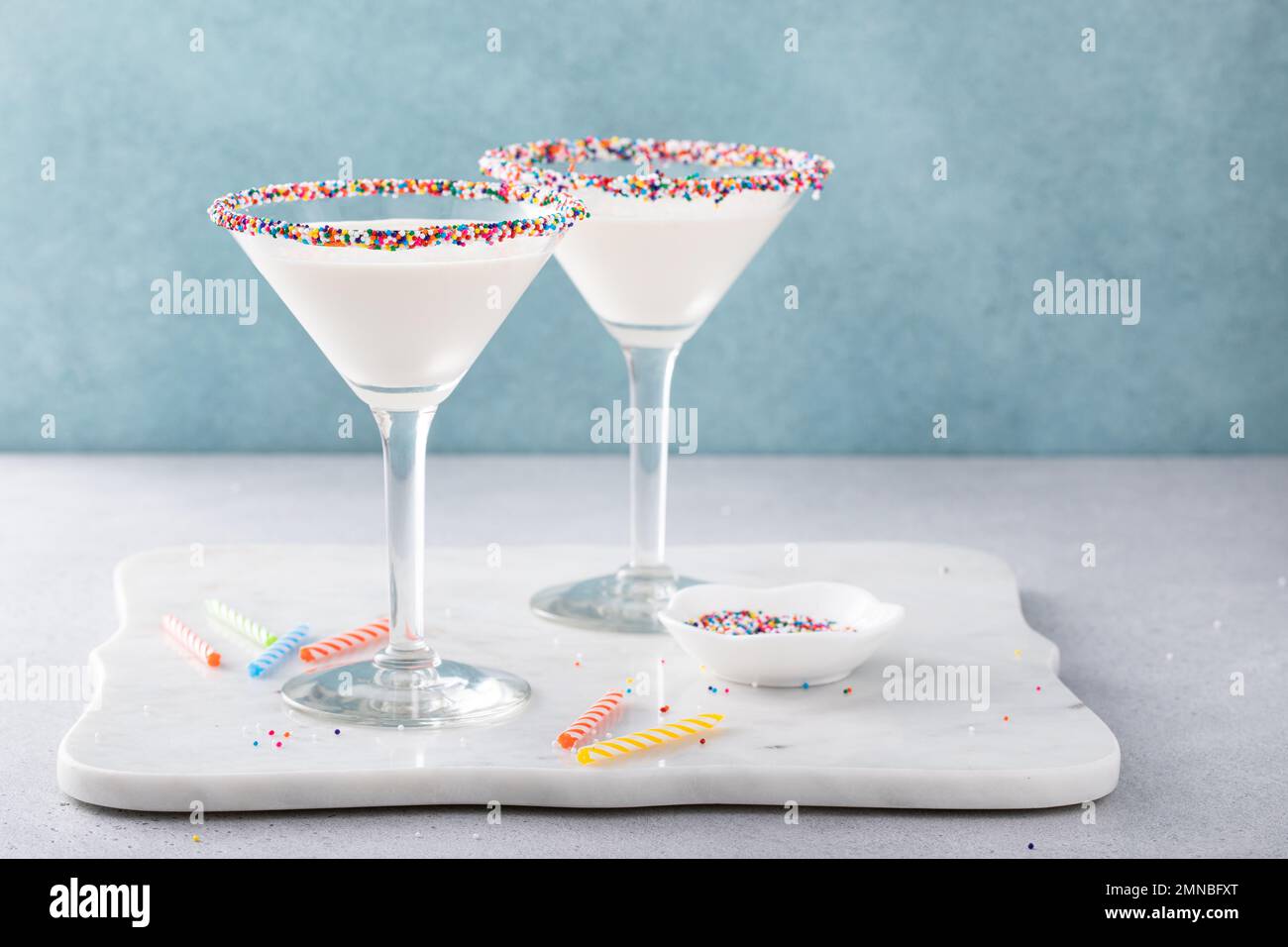 Torta di compleanno martini con spolverini sul bordo di vetro e candele di compleanno Foto Stock