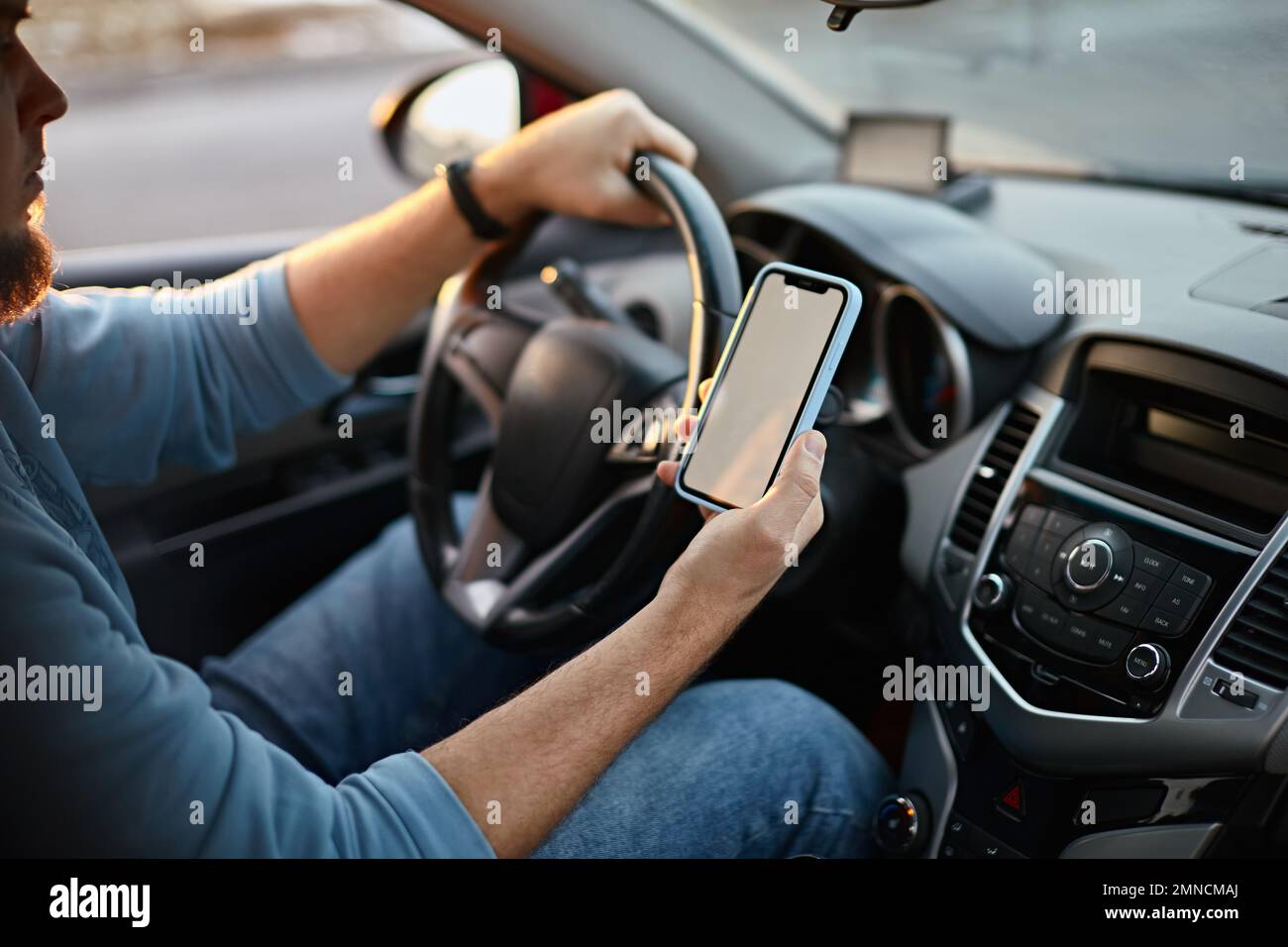 Uomo conducente che utilizza lo schermo del telefono cellulare mockup vuoto sulla strada durante la guida di un'auto Foto Stock