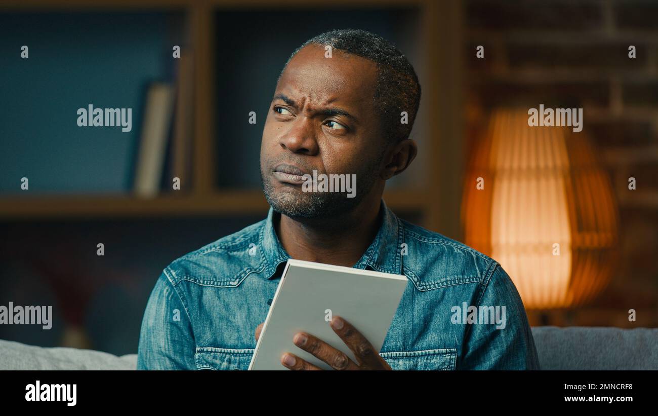 Uomo afroamericano adulto pensivo indoor pensare in profondità nei pensieri creare strategia uomo d'affari premuroso prendere appunti nella pianificazione del notebook Foto Stock