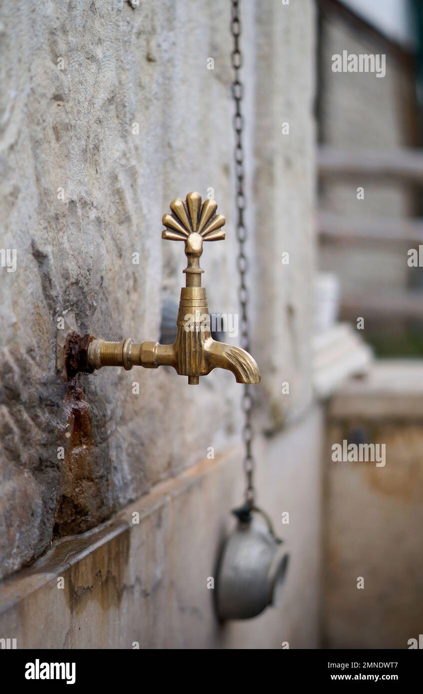 Una vecchia fontana di strada. Rubinetto in ottone. Foto Stock