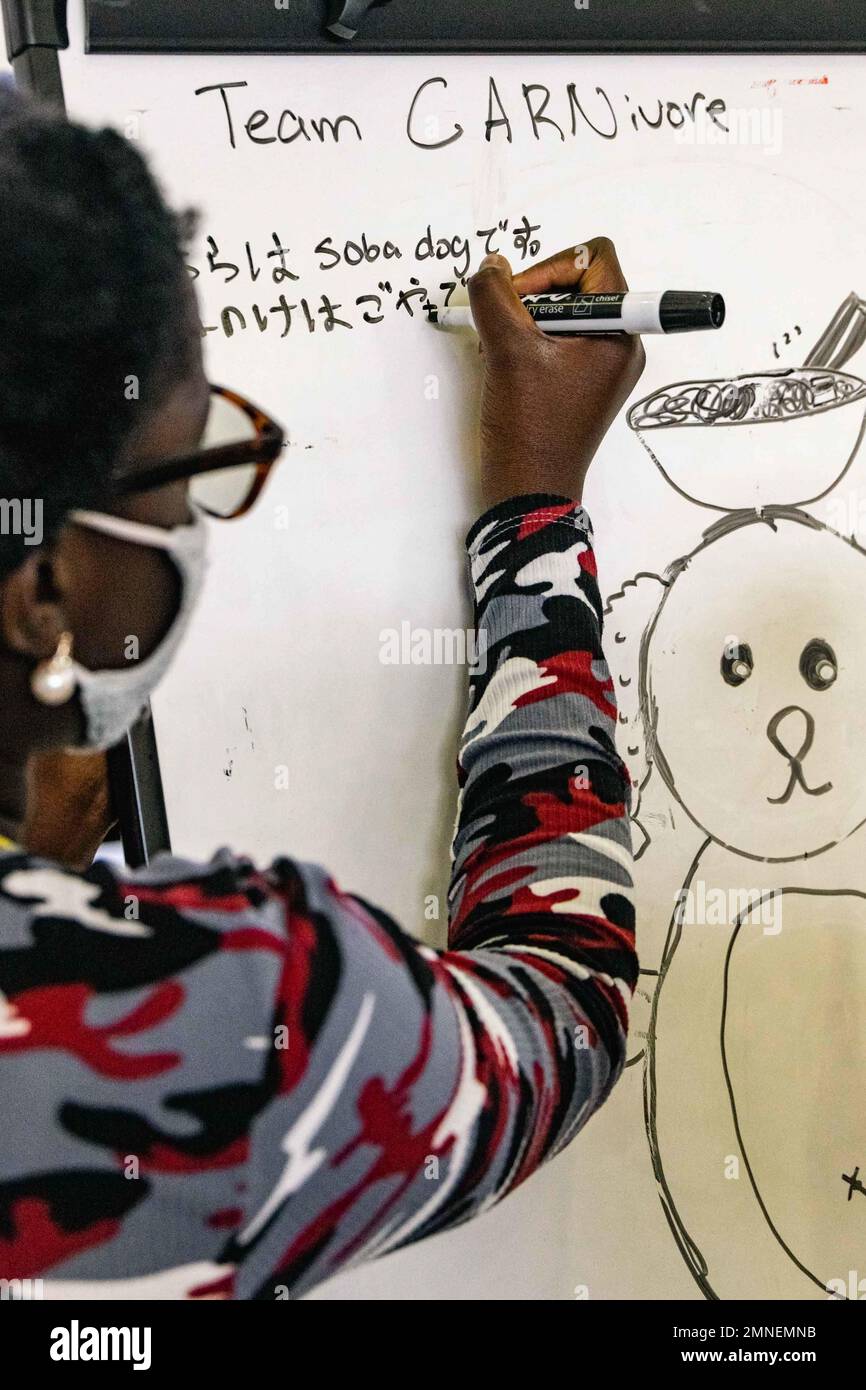 Uno studente scrive su una lavagna durante il programma di Scambio giovani del 2022 alla Scuola media di Camp Lester a Camp Lester, Okinawa, Giappone, 2 ottobre 2022. Il programma è stato organizzato dal Ministero degli Affari Esteri e dal Dipartimento della Difesa Education Activity, che ha permesso ai partecipanti sia giapponesi che statunitensi di praticare sane capacità comunicative e di partecipare ad attività per conoscere meglio le rispettive culture. Gli studenti crearono mascotte culturalmente unite, ricevettero premi e stabilirono amicizie durature. Foto Stock