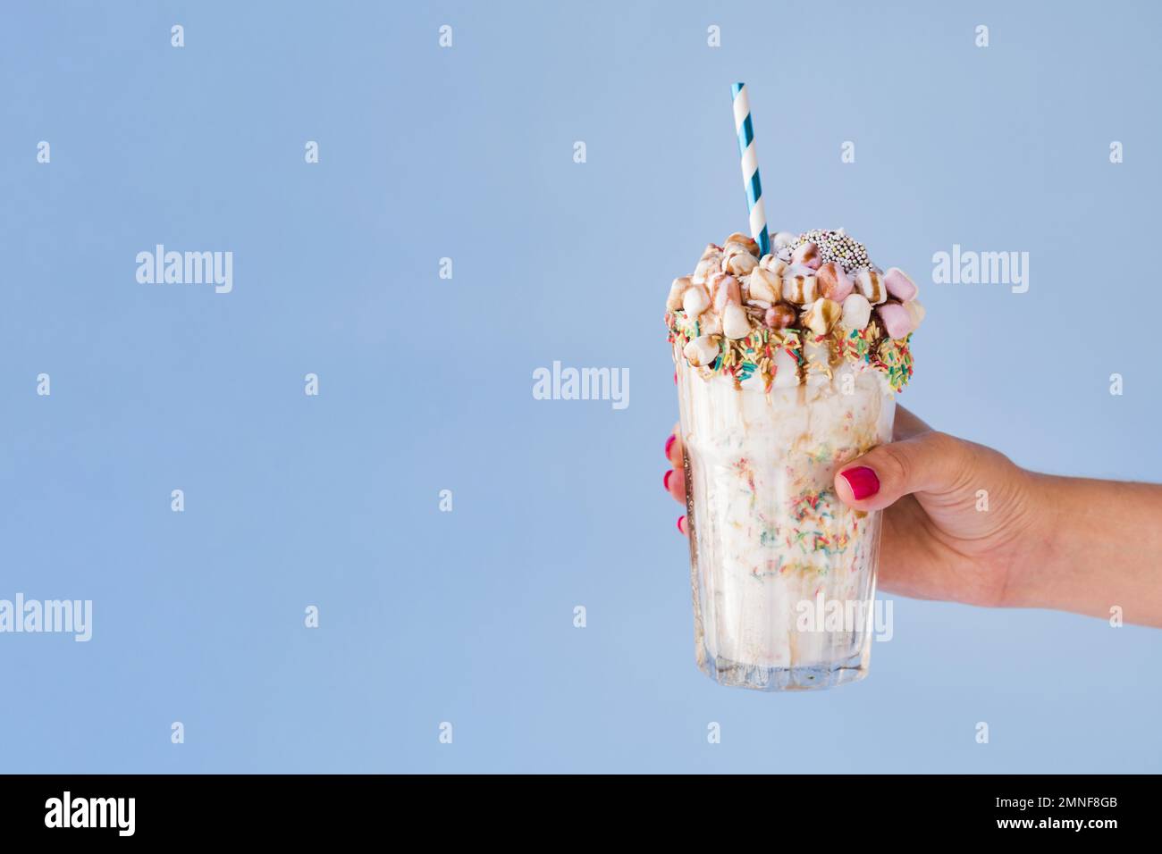 vista frontale mano che tiene il milkshake con sfondo blu. Risoluzione e foto di alta qualità Foto Stock