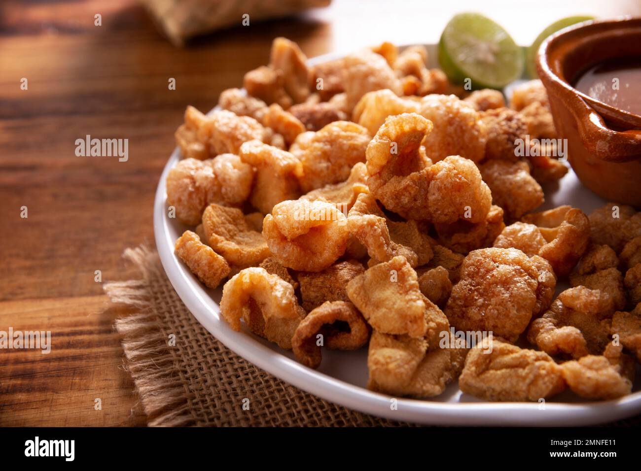 Chicharrones. Croste di maiale fritte, pezzi di pelle di maiale croccanti, ingrediente tradizionale messicano o snack servito con succo di limone e salsa di peperoncino rosso caldo. Foto Stock