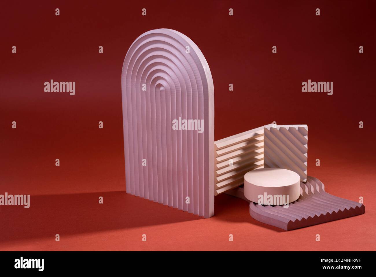 Composizione di podi geometrici o di colonnine di colore rosa sporco contro il rosso. Sfondo minimo per la visualizzazione della presentazione del prodotto cosmetico. Foto Stock