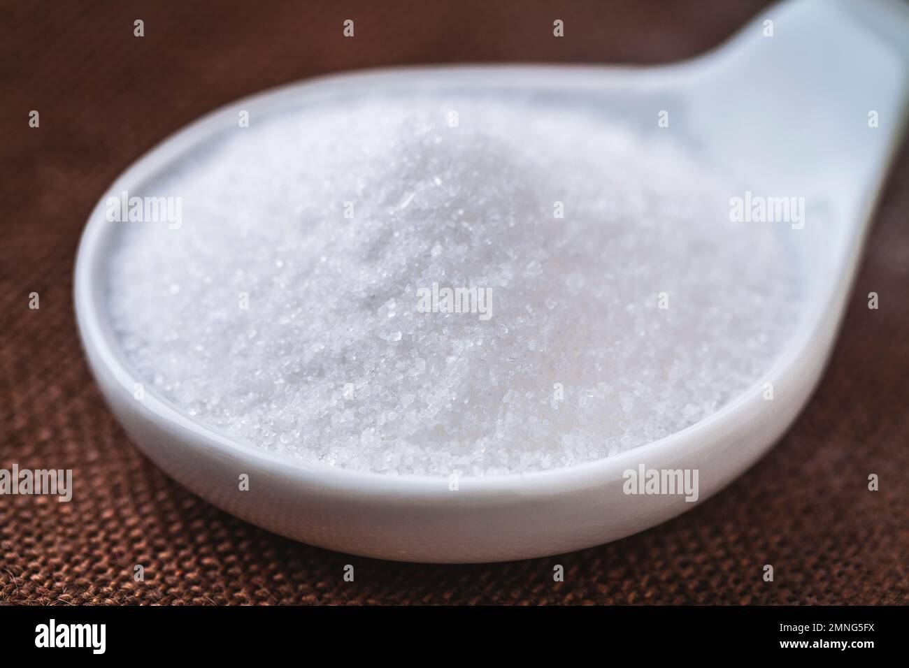 Zucchero bianco raffinato in una ciotola sullo sfondo Foto Stock